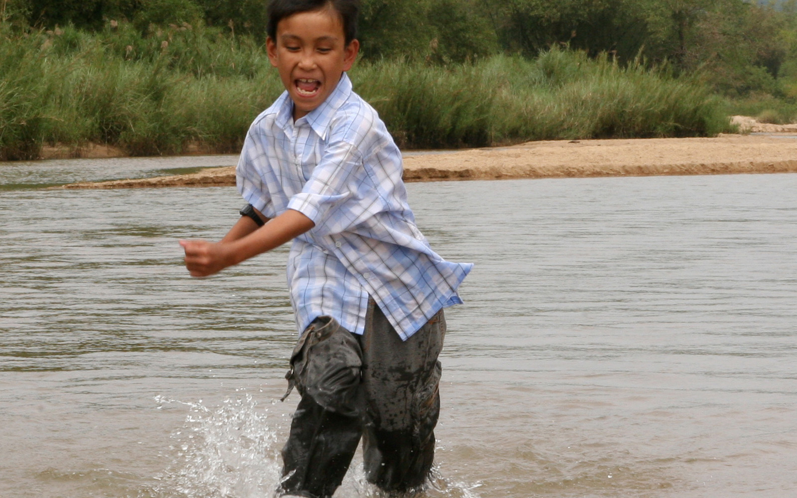 boy wearing checkered polo running in the water