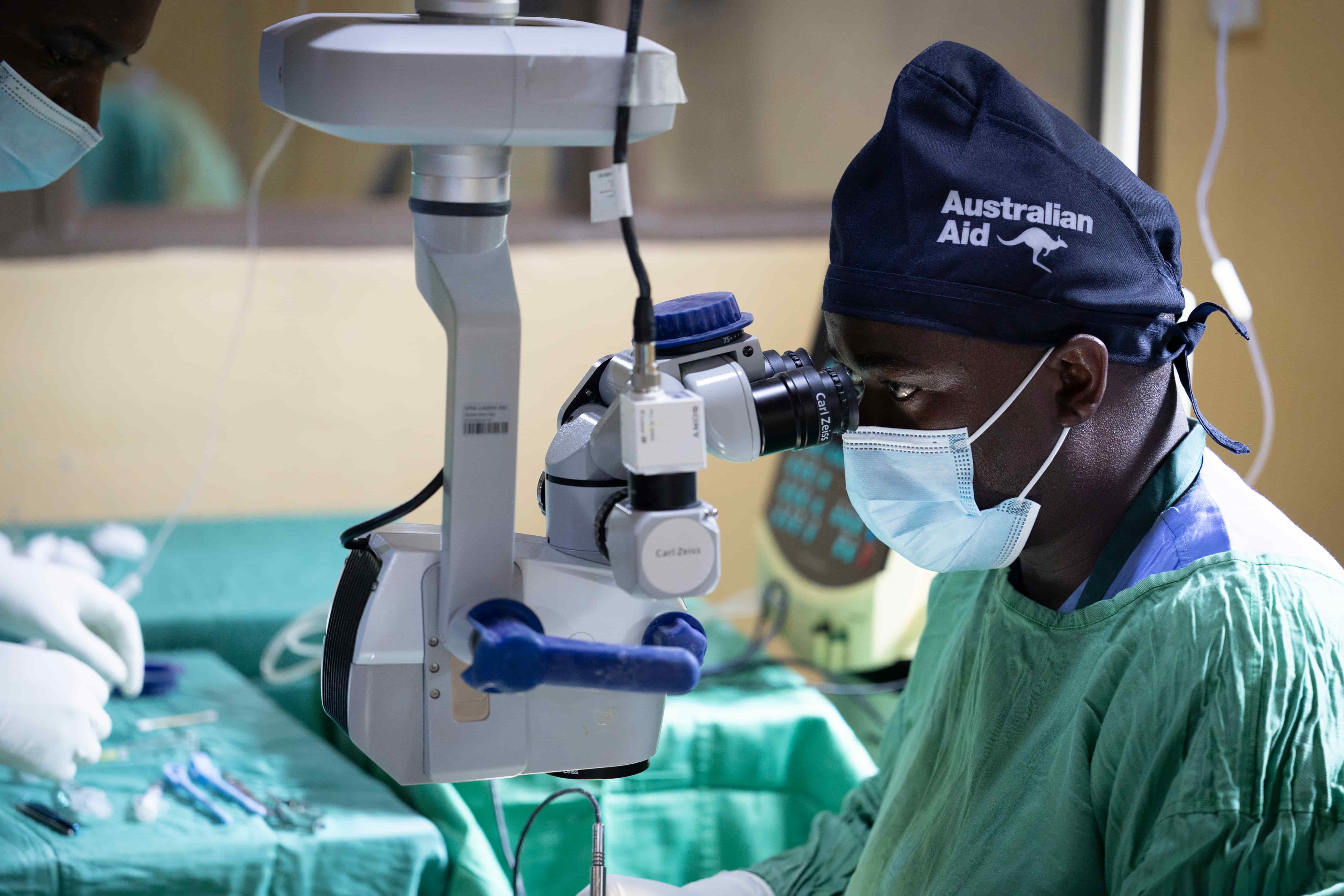 Dr Tuyisabe Theophile, a paediatric ophthalmologist, performing cataract surgery on a young patient in Rwanda, focused and carefully using surgical instruments in a clinical setting.