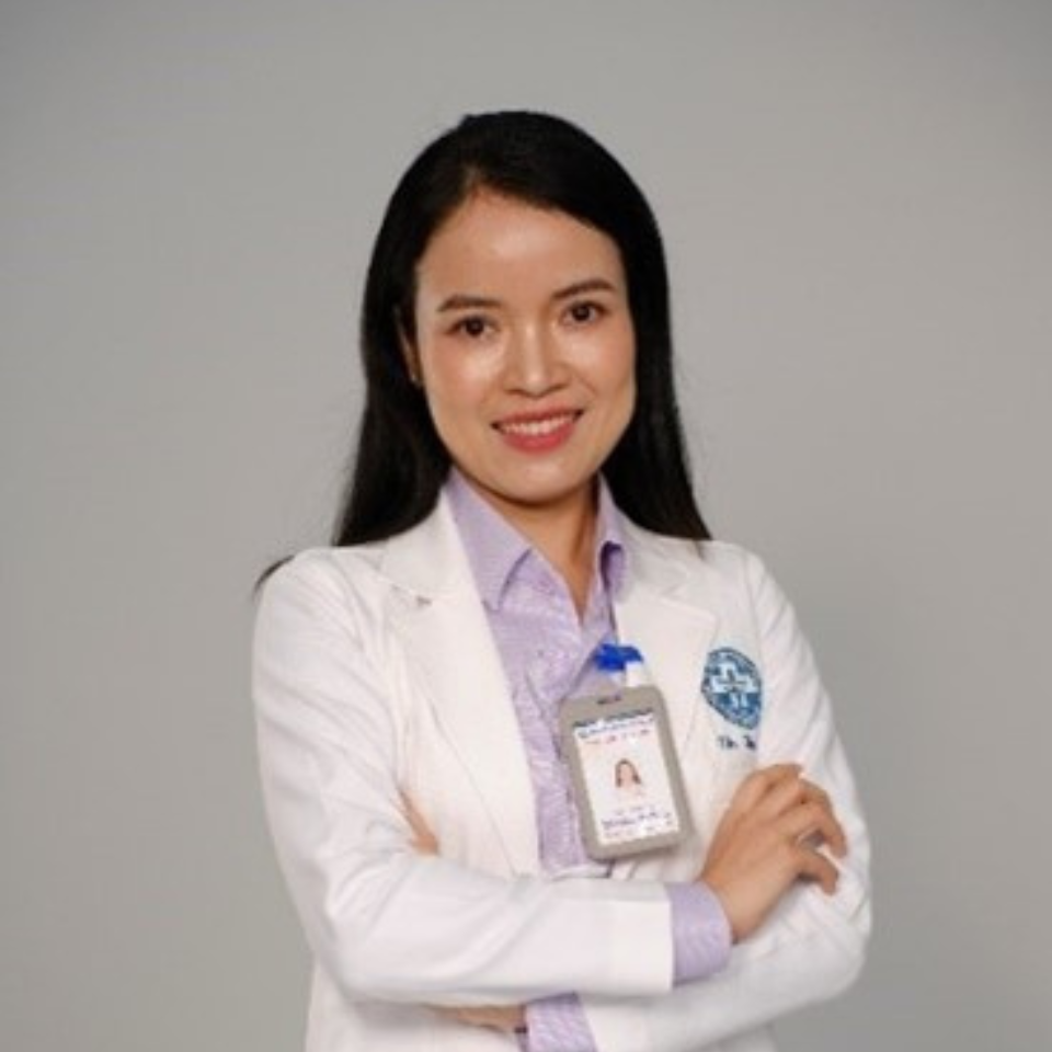 A portrait photo of Dr Tran in a white lab coat, standing with her arms crossed and smiling at the camera. 