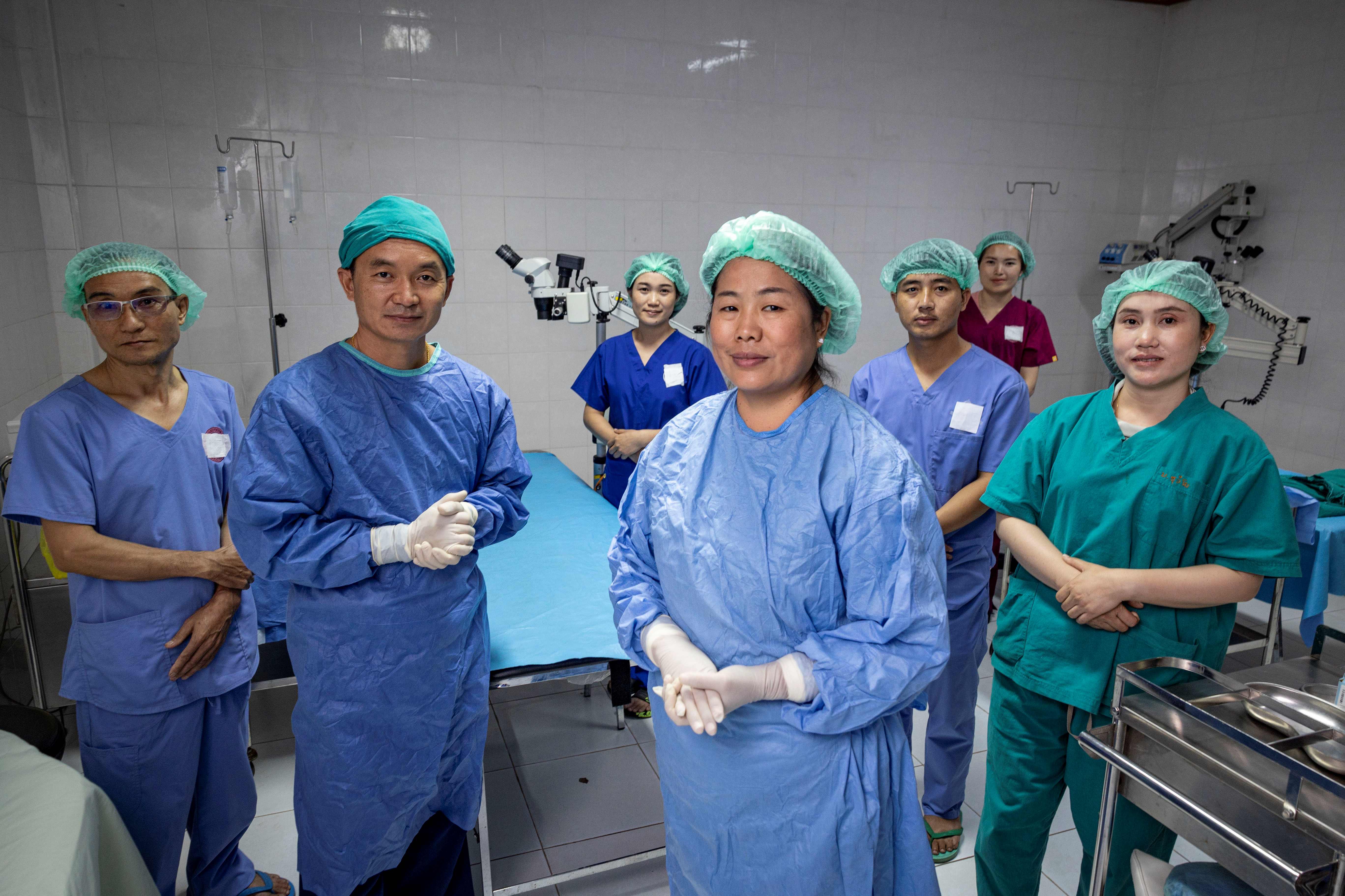 Dr Senglar (centre) dressed in scrubs, posing in a Loas surgical ward with her team in the background.