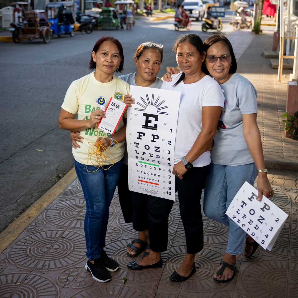 An image of four female community health workers as they go house to house screening people for eye health. 