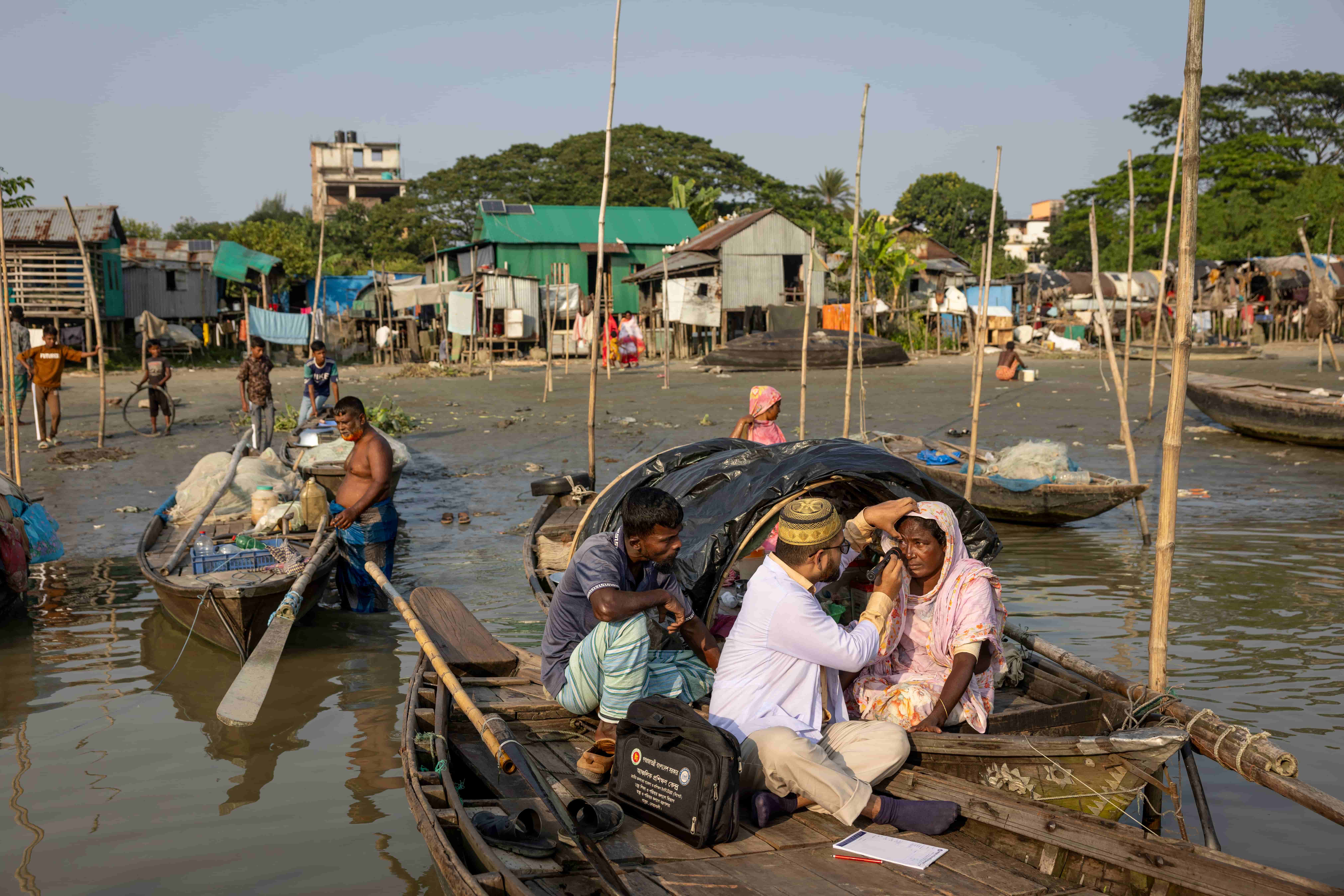 Woman from a Bede community in Bangladesh sits on her boat as a visiting medical team screens her eyes, bringing care directly to people living on the water.