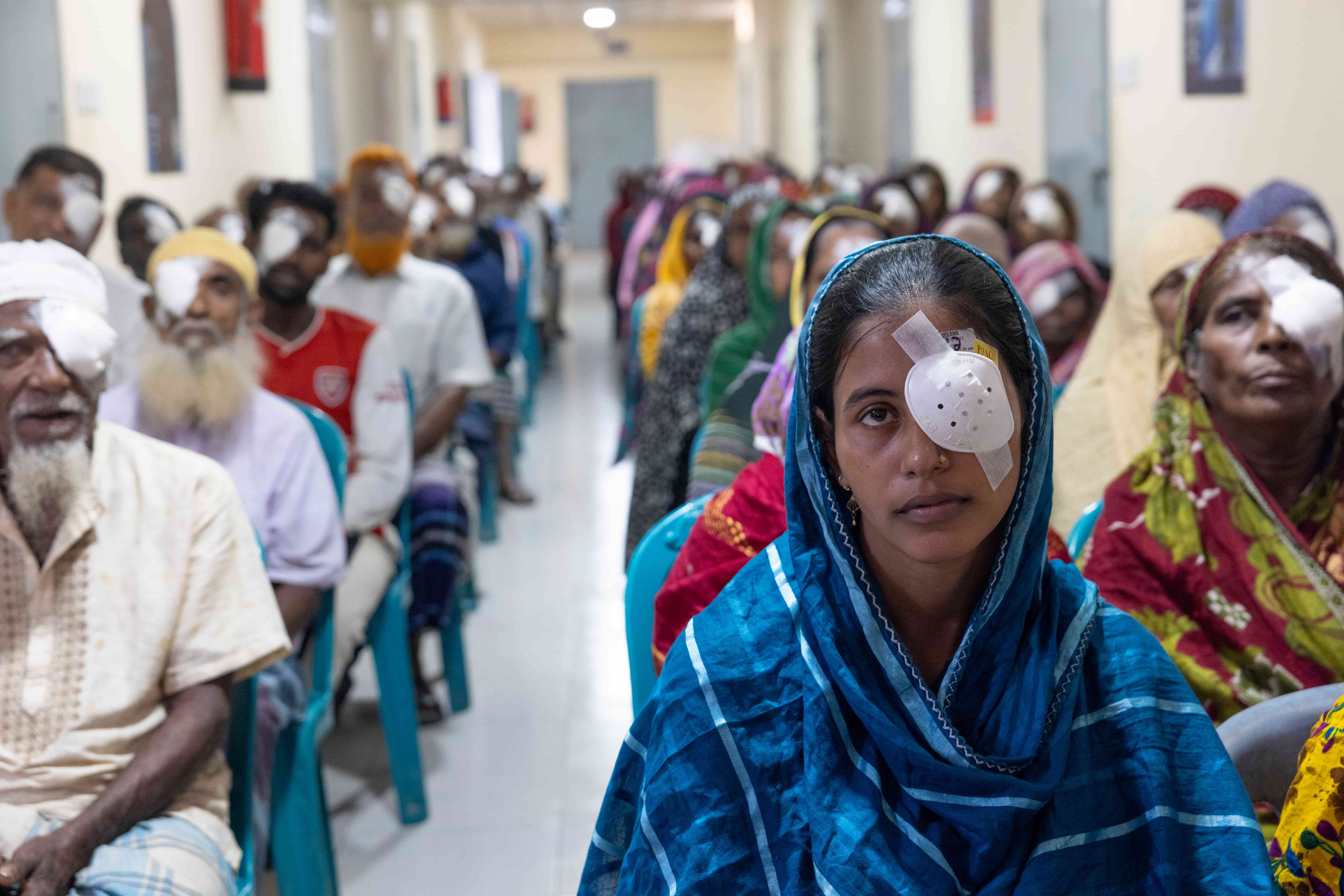 Parveen post surgery with an eye patch on. Other recipients of eye surgery sit behind her.