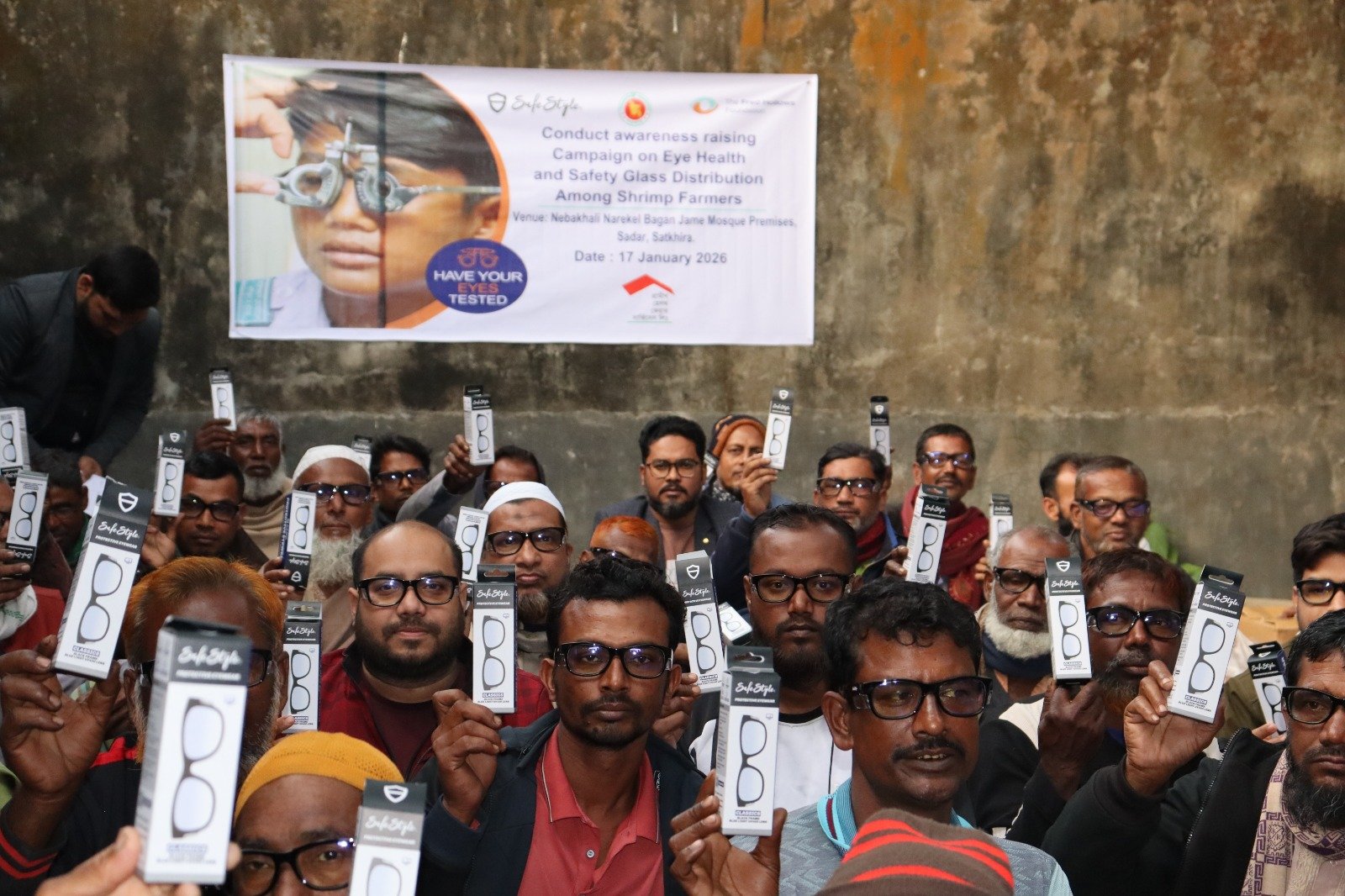 Workers in a shrimp farming community holding up new glasses as part of an eye health program to protect their vision
