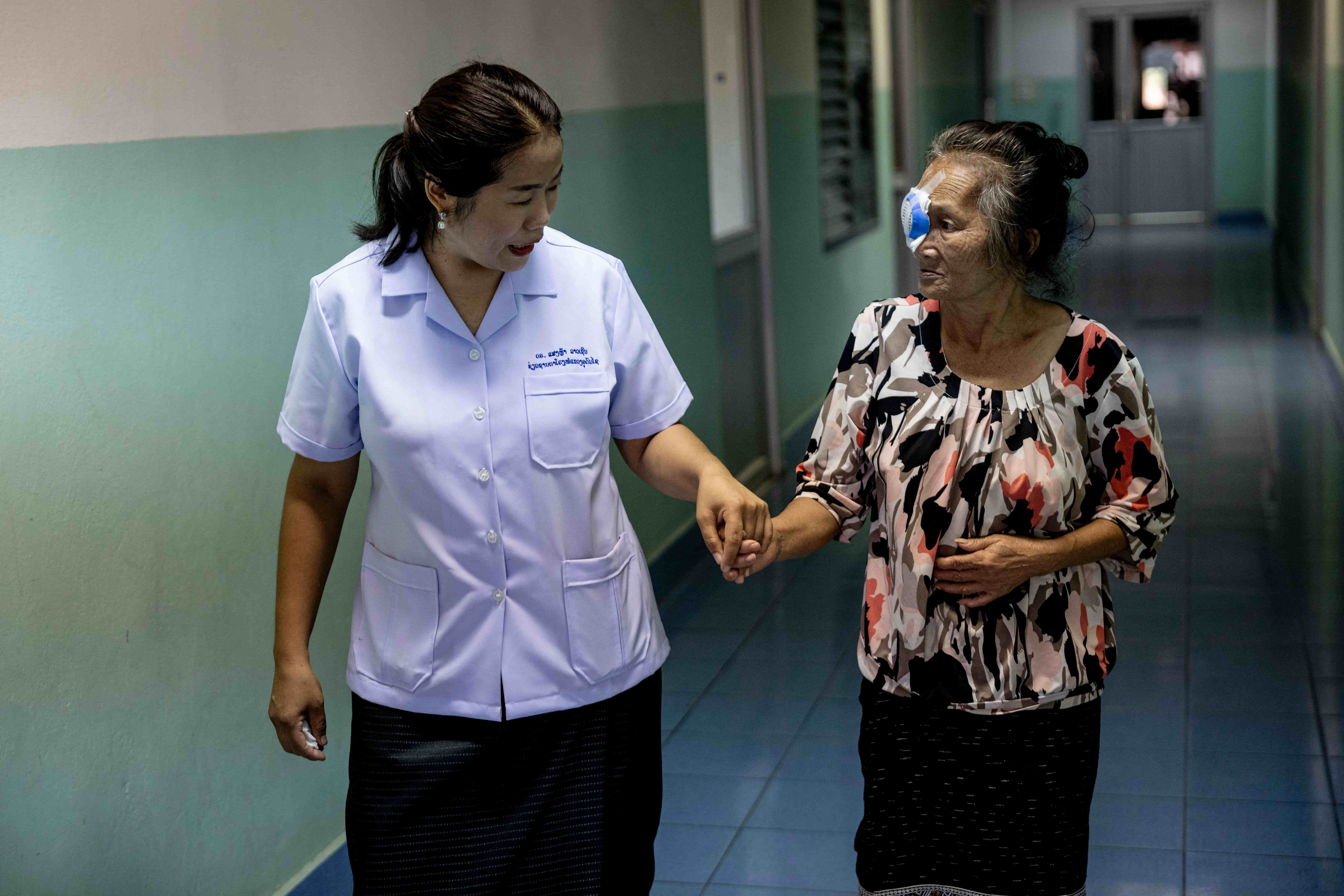 Dr Senglar gently holds the hand of Yerng, a 78-year-old from the Hmong indigenous community, following her cataract surgery at Oudomxay Eye Hospital in northern Laos.