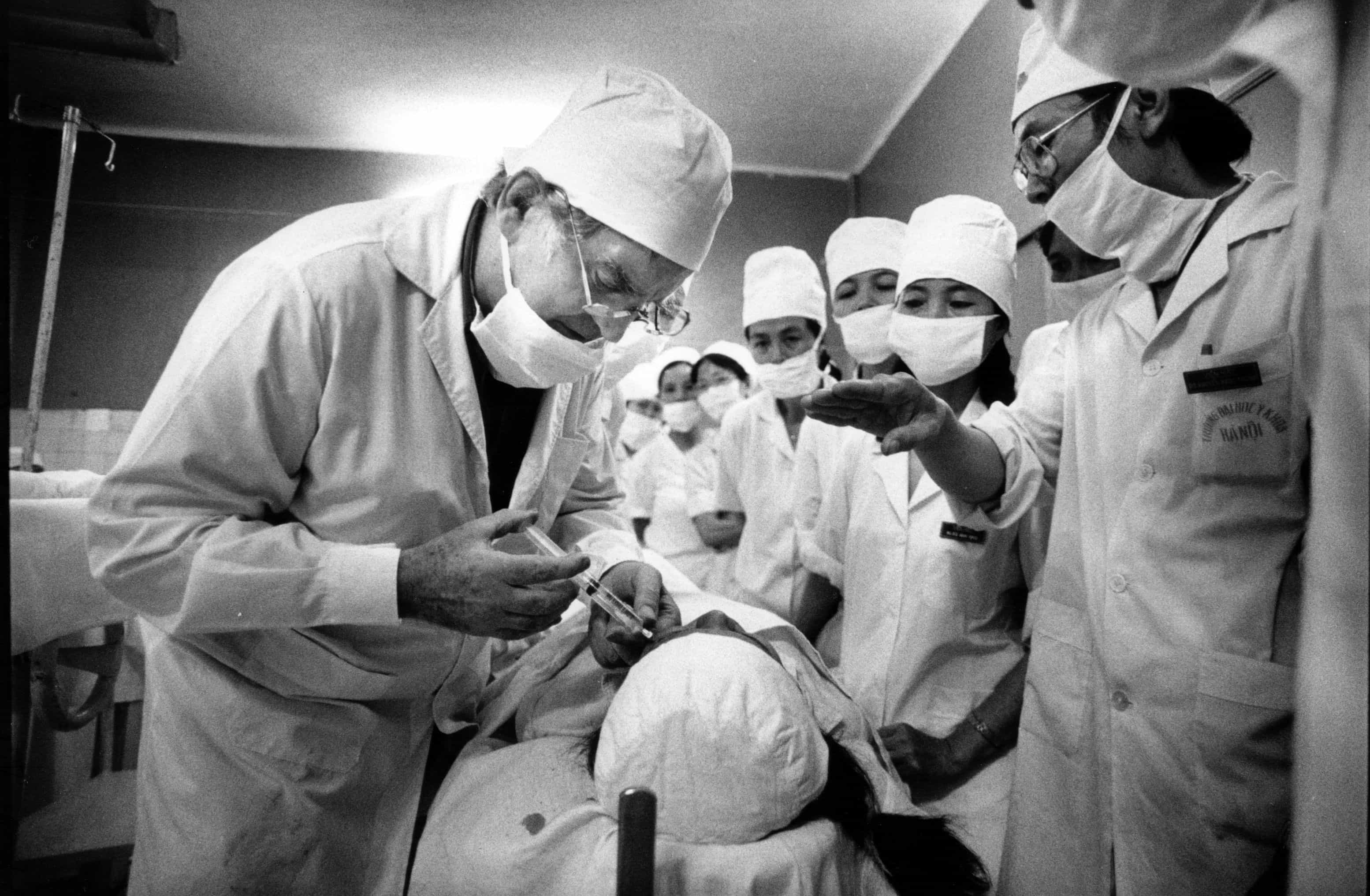 Fred Hollows operating during a training program in Vietnam, with local doctors observing and learning skills that would go on to restore sight for thousands.