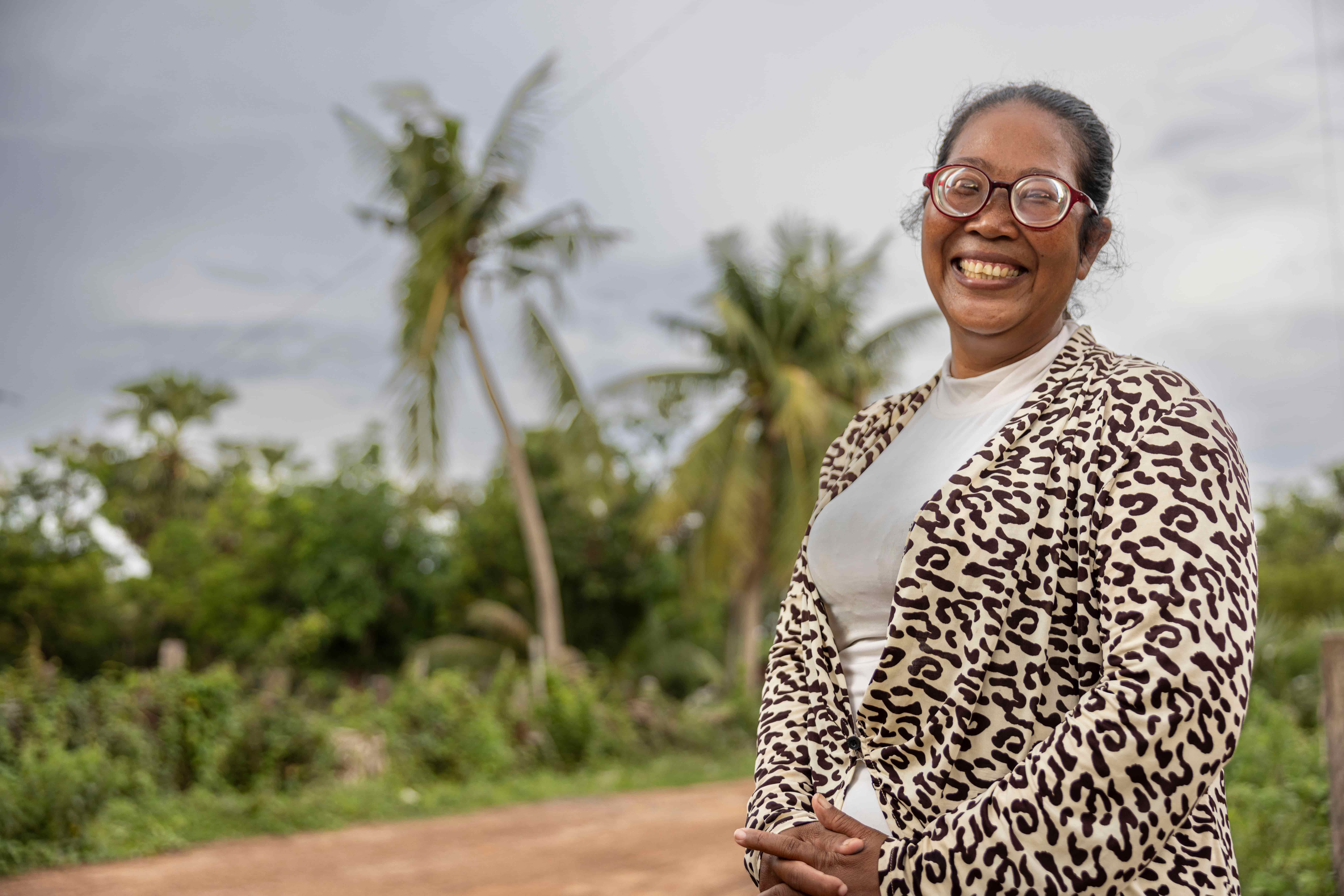 Chanthoeun smiles at the camera wearing her new prescription glasses in Boribo district, Cambodia. After nearly 30 years of blurred vision, access to eye care has helped her care for her children, support their learning and run her small business.