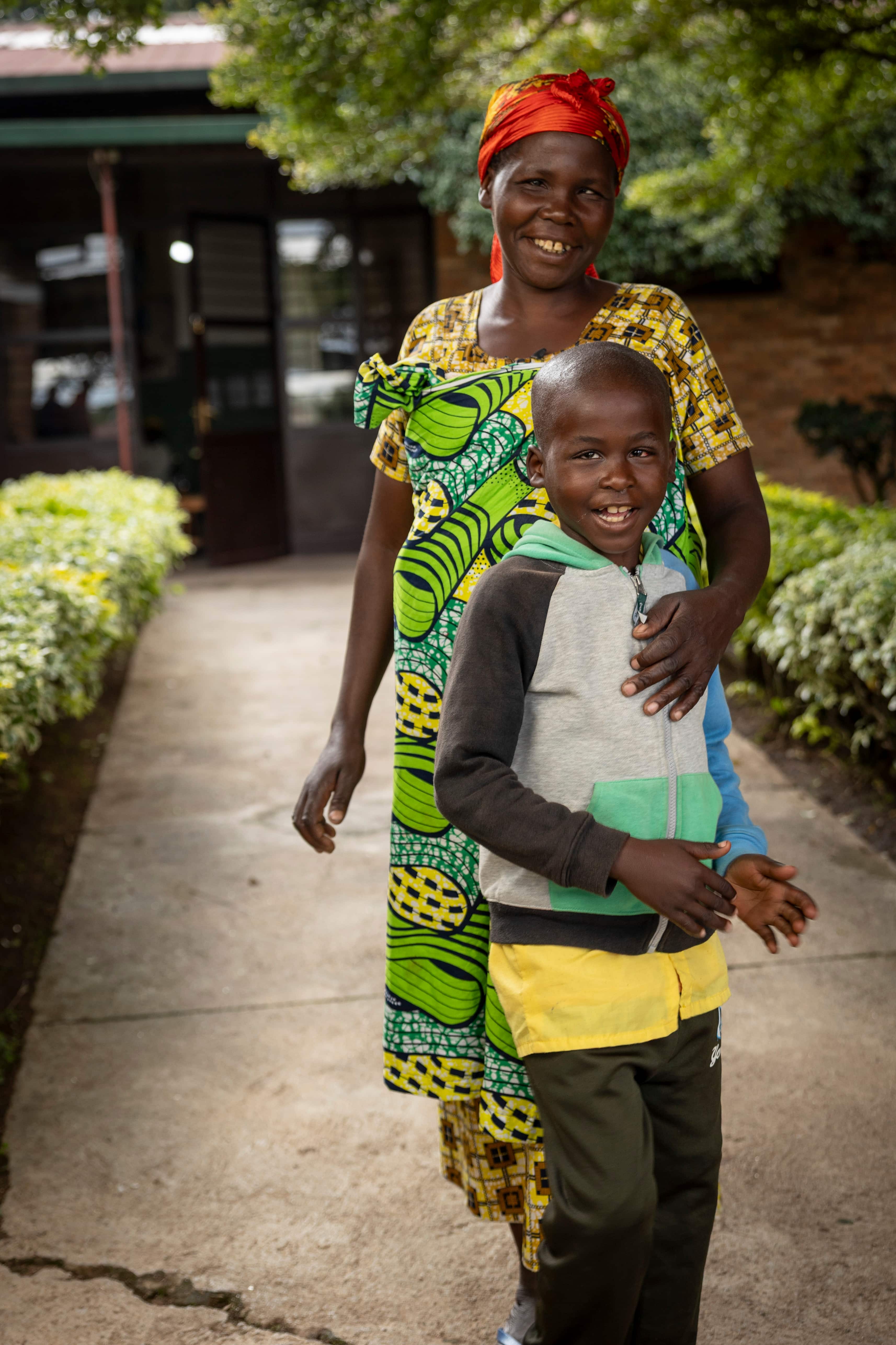 Juliette stands with her son Raban outside Kabgayi Eye Unit in Rwanda after his sight-restoring surgery. Following years of vision challenges that affected school, home life and church, Raban is now hopeful for a brighter future and the chance to return to everyday activities with confidence.