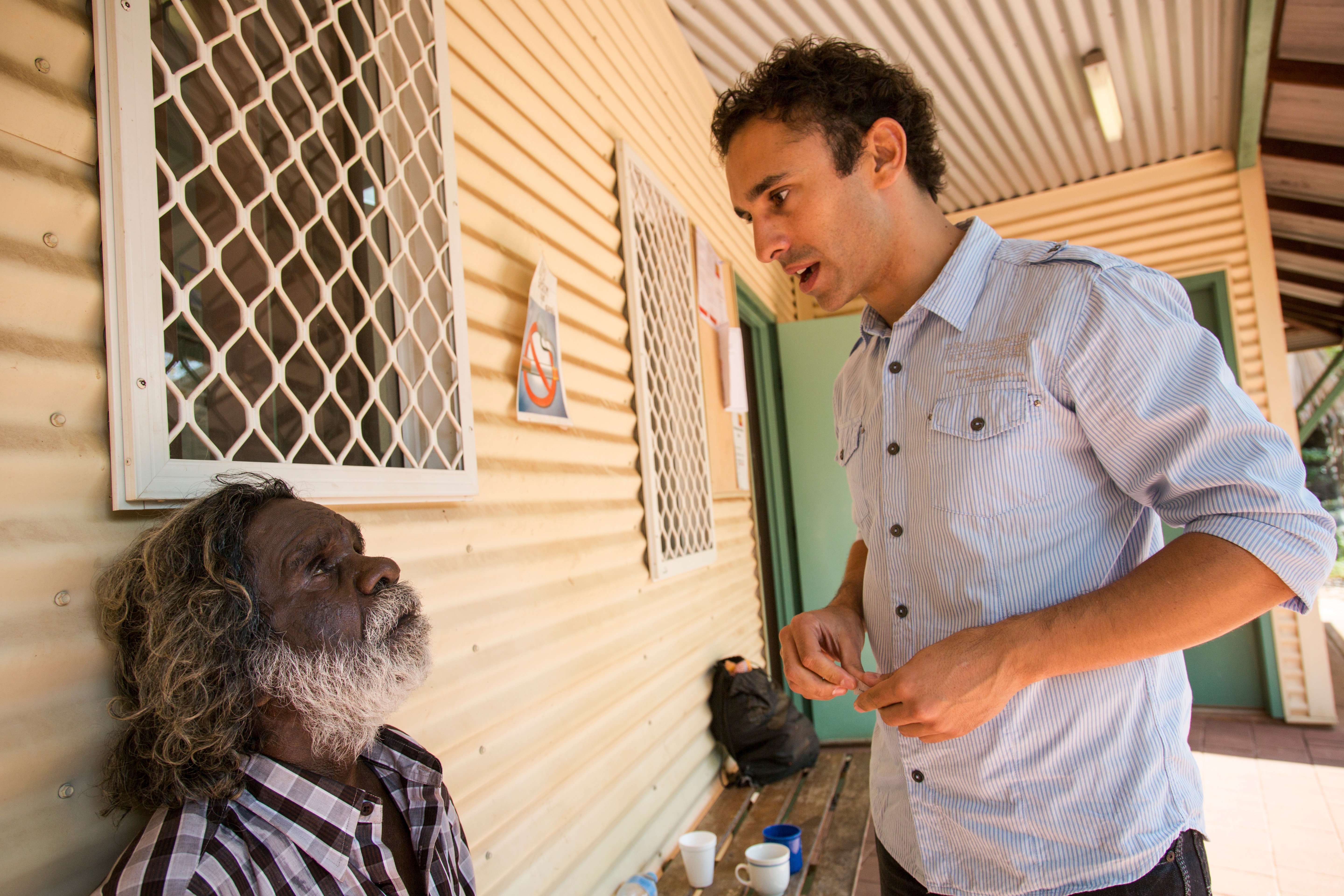 Dr Kris Rallah talking to an Indigenous patient outside a remote eye health facility. 