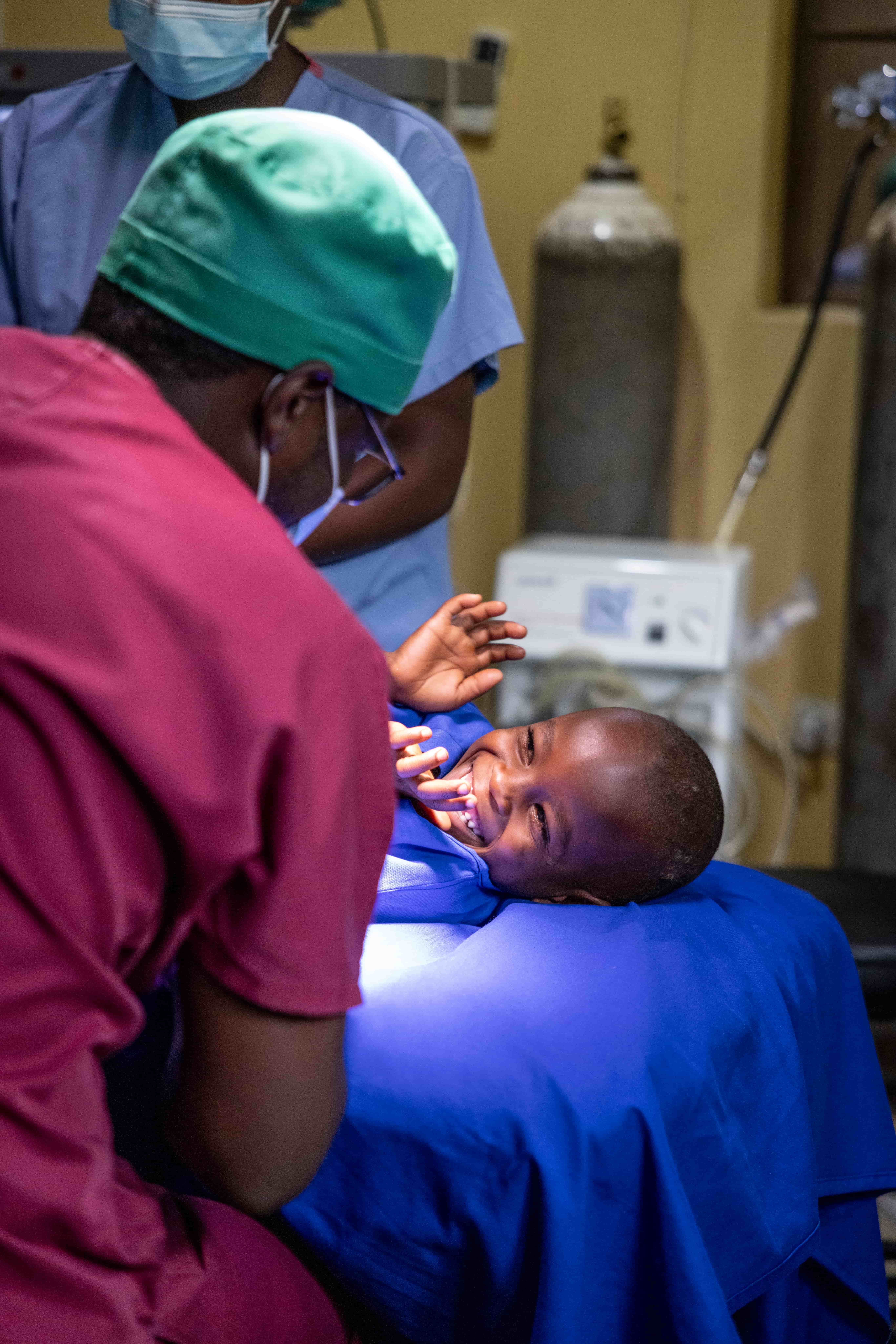 Blaise lies on the surgery bed, smiling widely as he gets ready for his cataract operation.