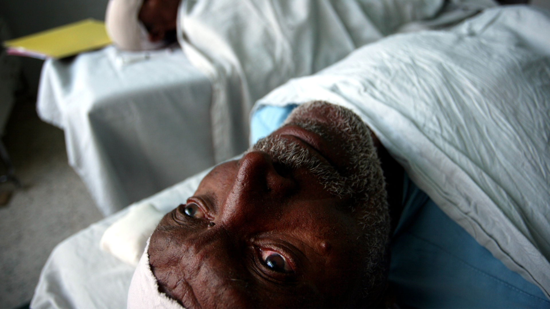 A man with myopia lying on a hospital bed in Eritrea, 2004. 