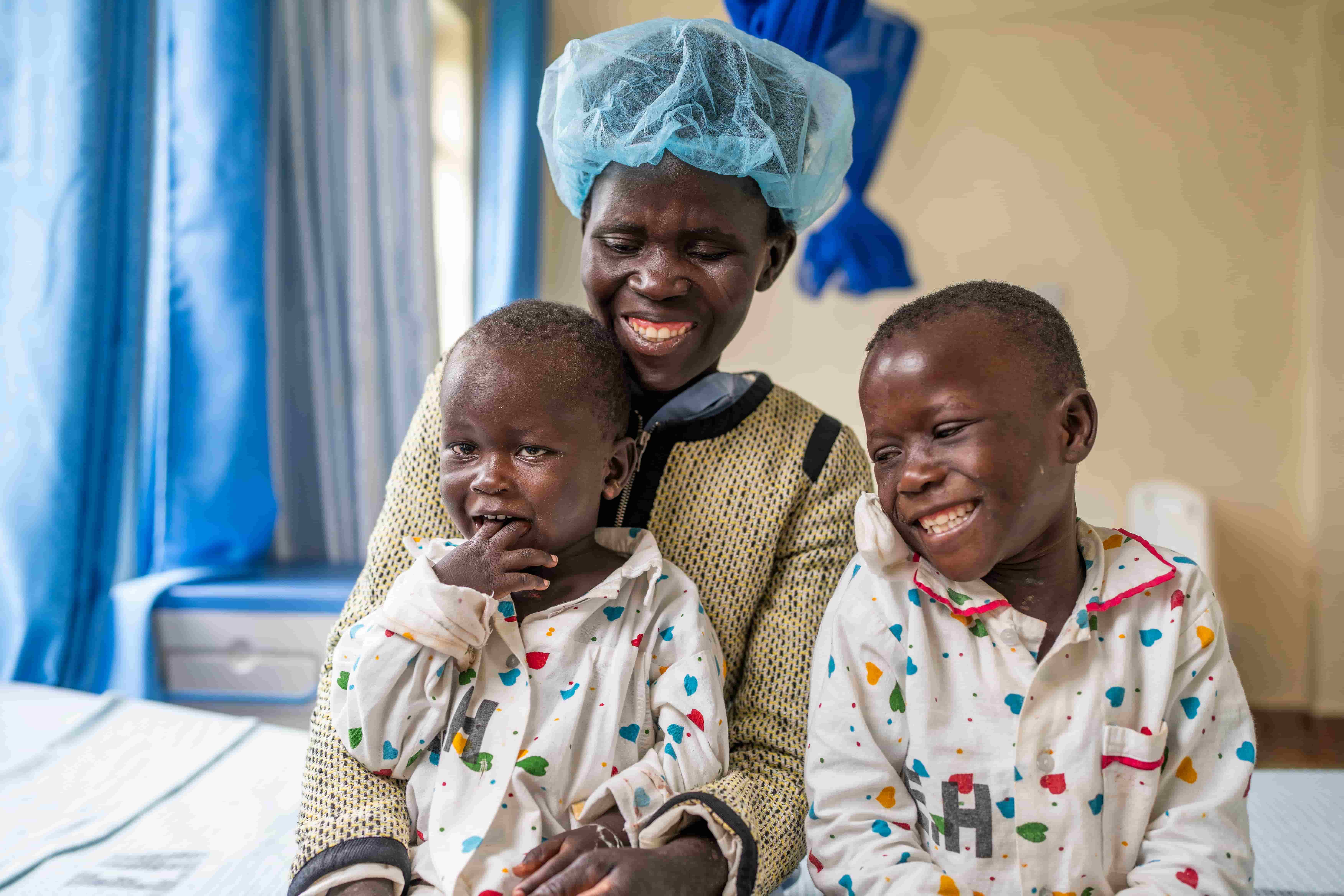 Eveline, Ruth and Vincent cuddling together at a hospital after eye surgery