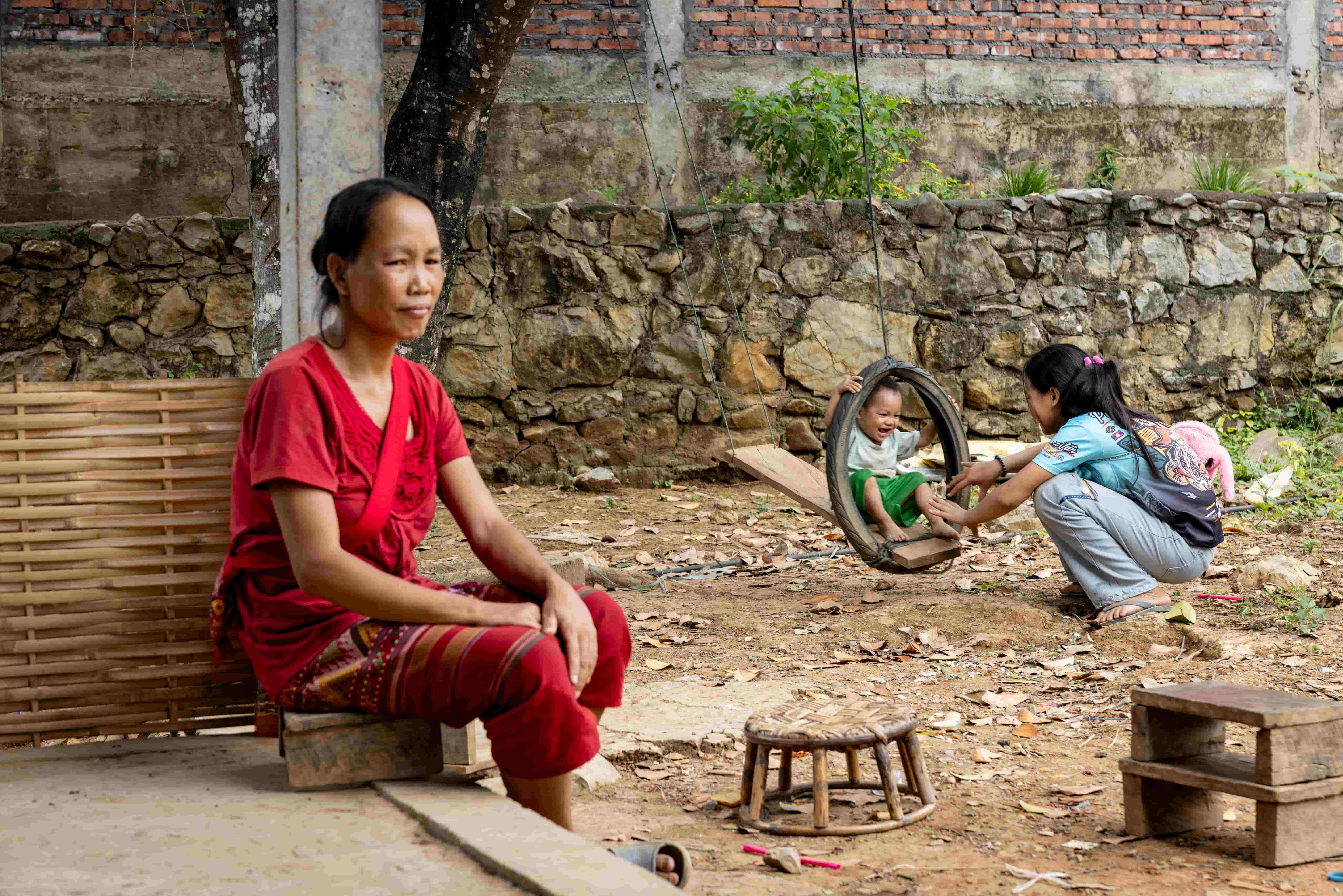 Lien waits for cataract surgery in Oudomxay, Laos, as her children play nearby, hoping to see them clearly again with the help of The Fred Hollows Foundation.