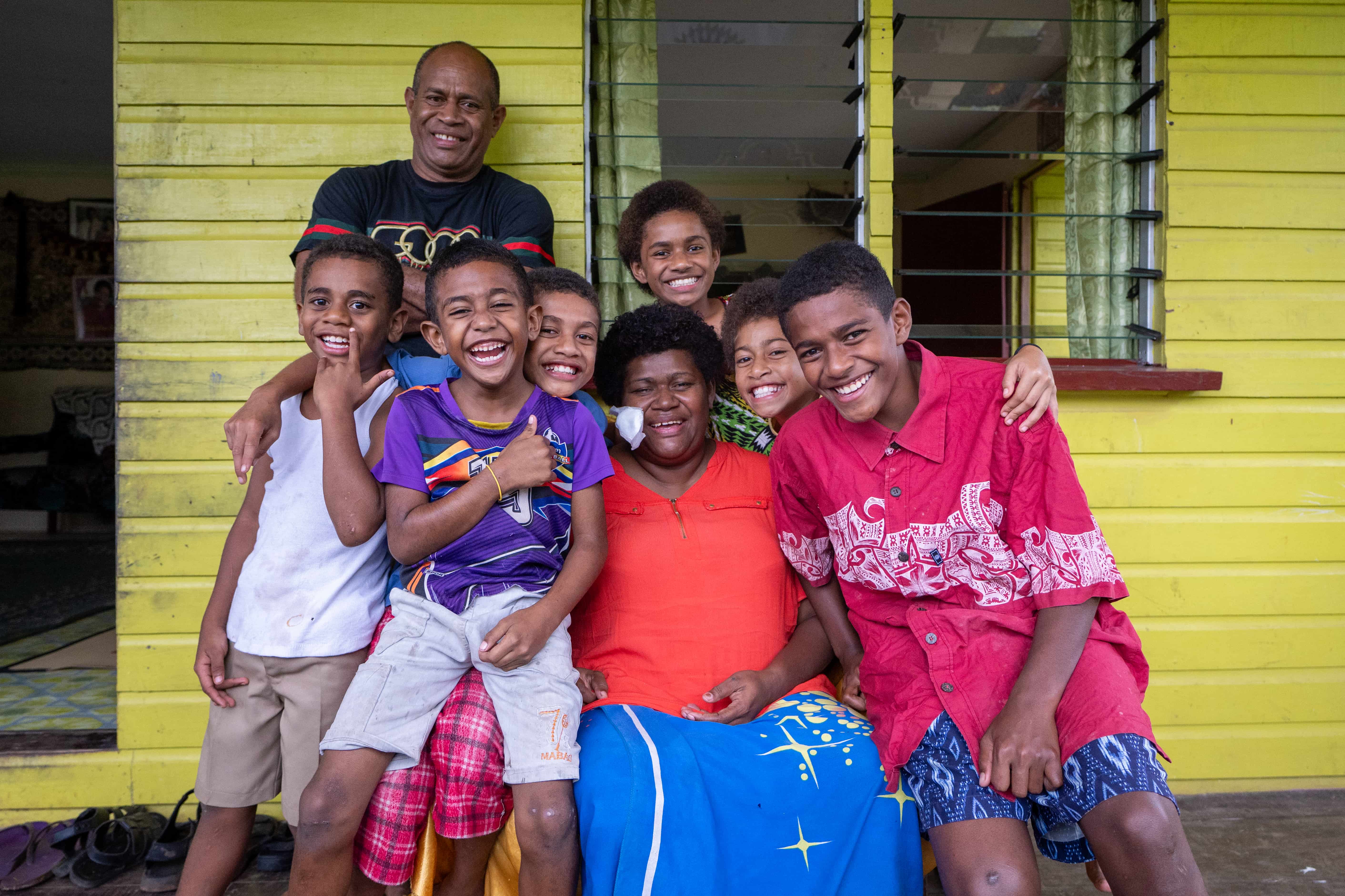 A mother with an eye patch, surrounded by her six children and husband in Fiji.