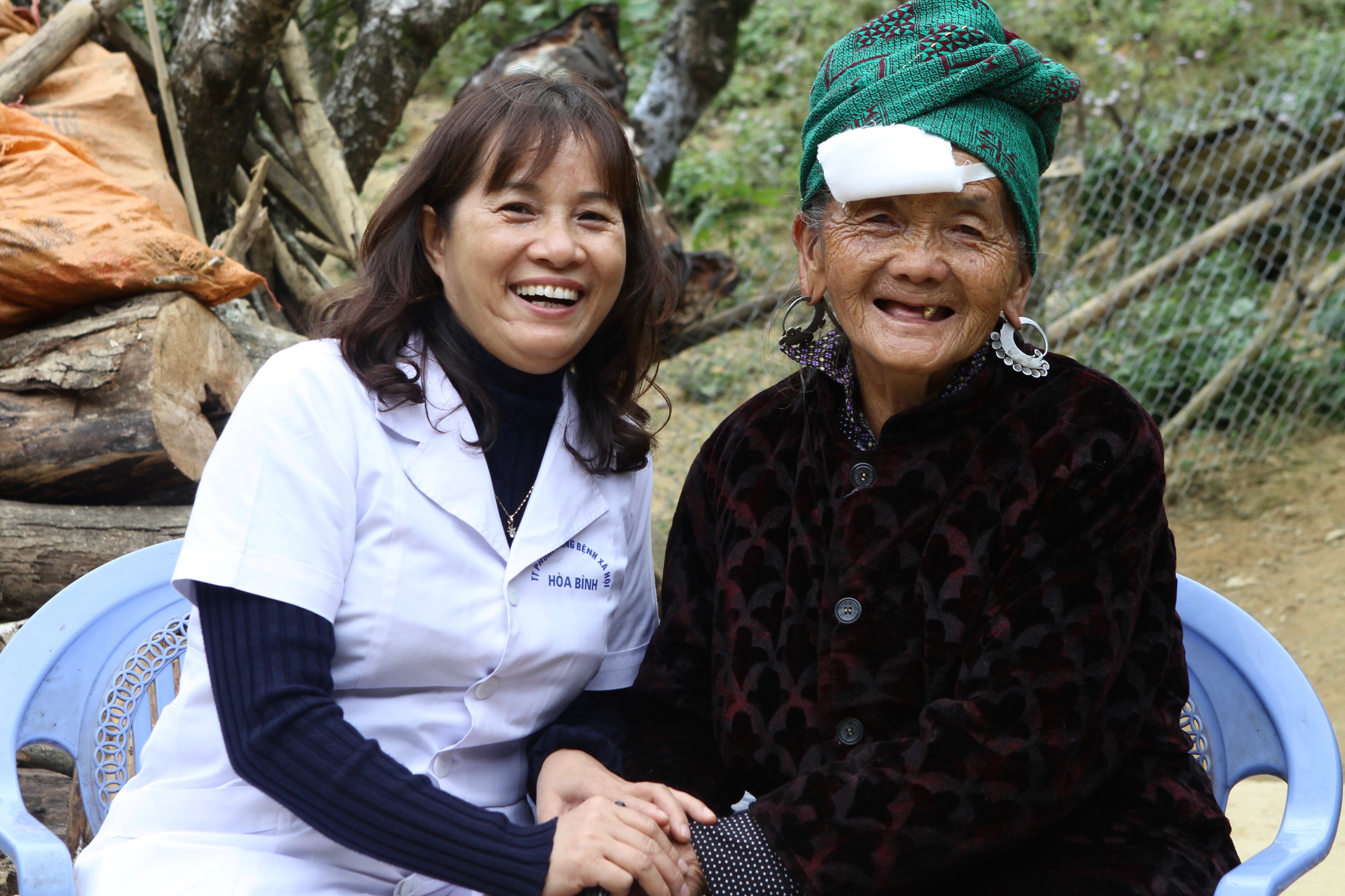Grandmother Sung smiles and holds the hand of the surgeon who performed her cataract operation.