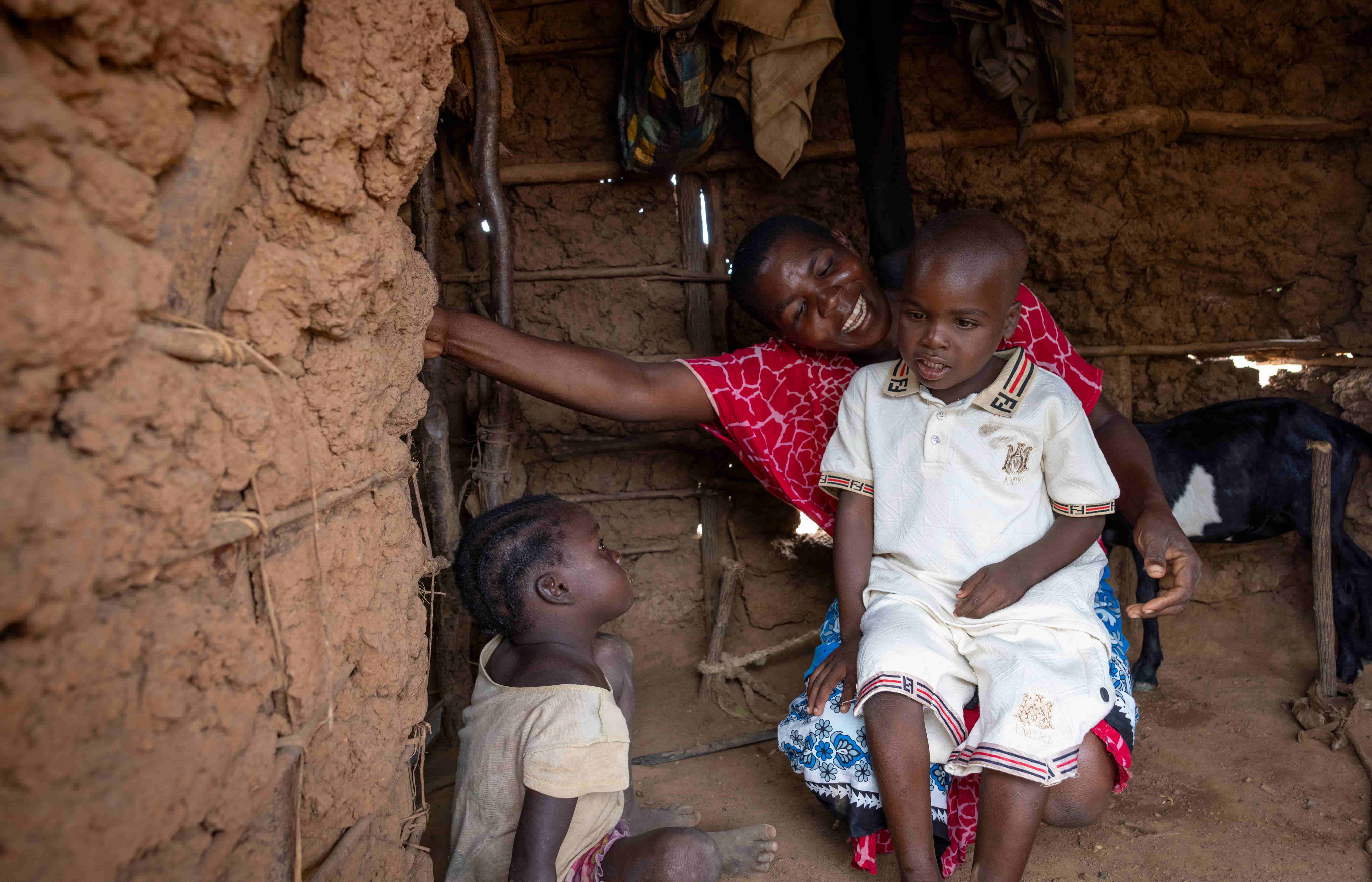 Jira sitting with his mother inside his mud brick home in remote Kenya.