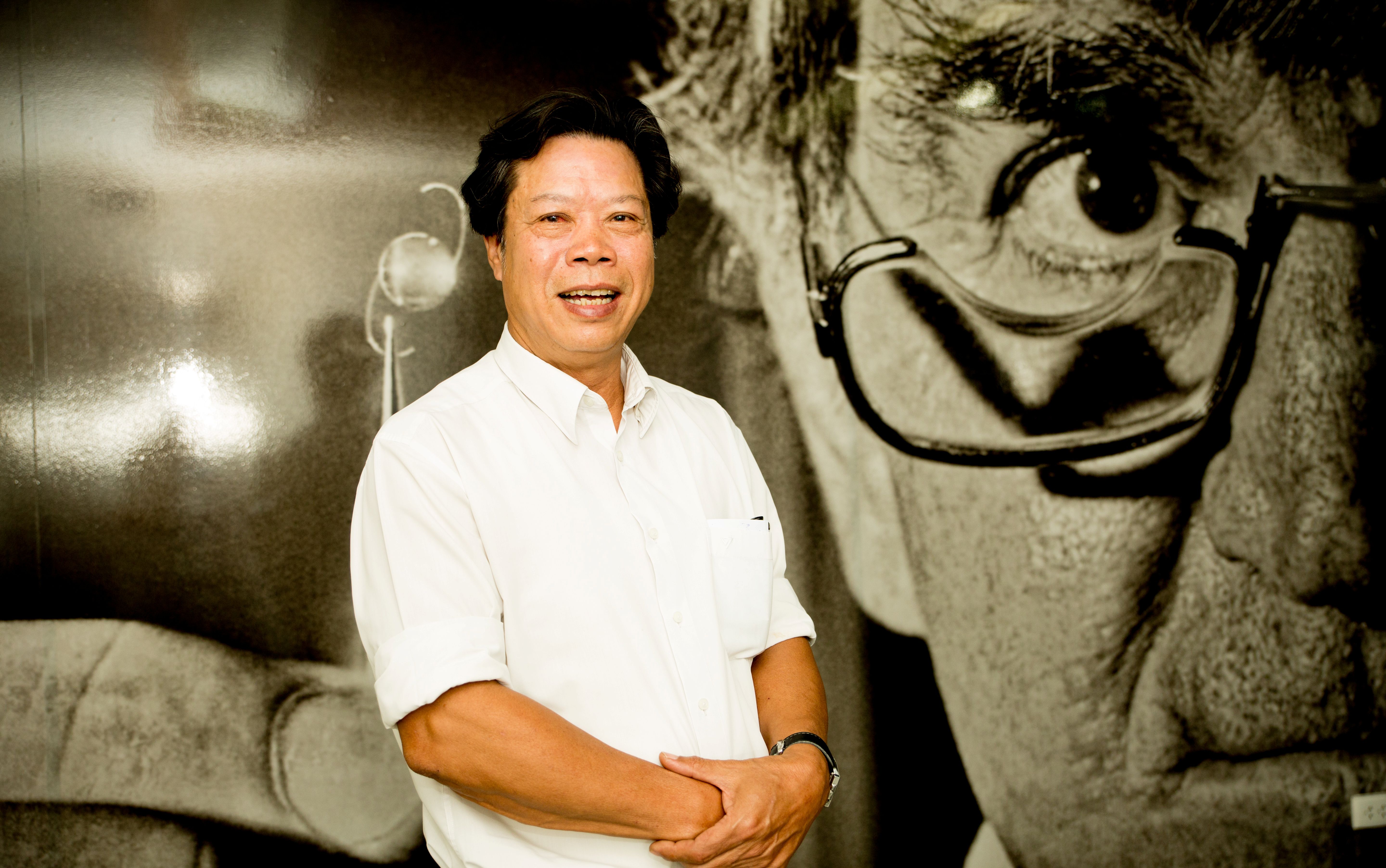 Dr Binh posing in front of a Fred Hollows portrait