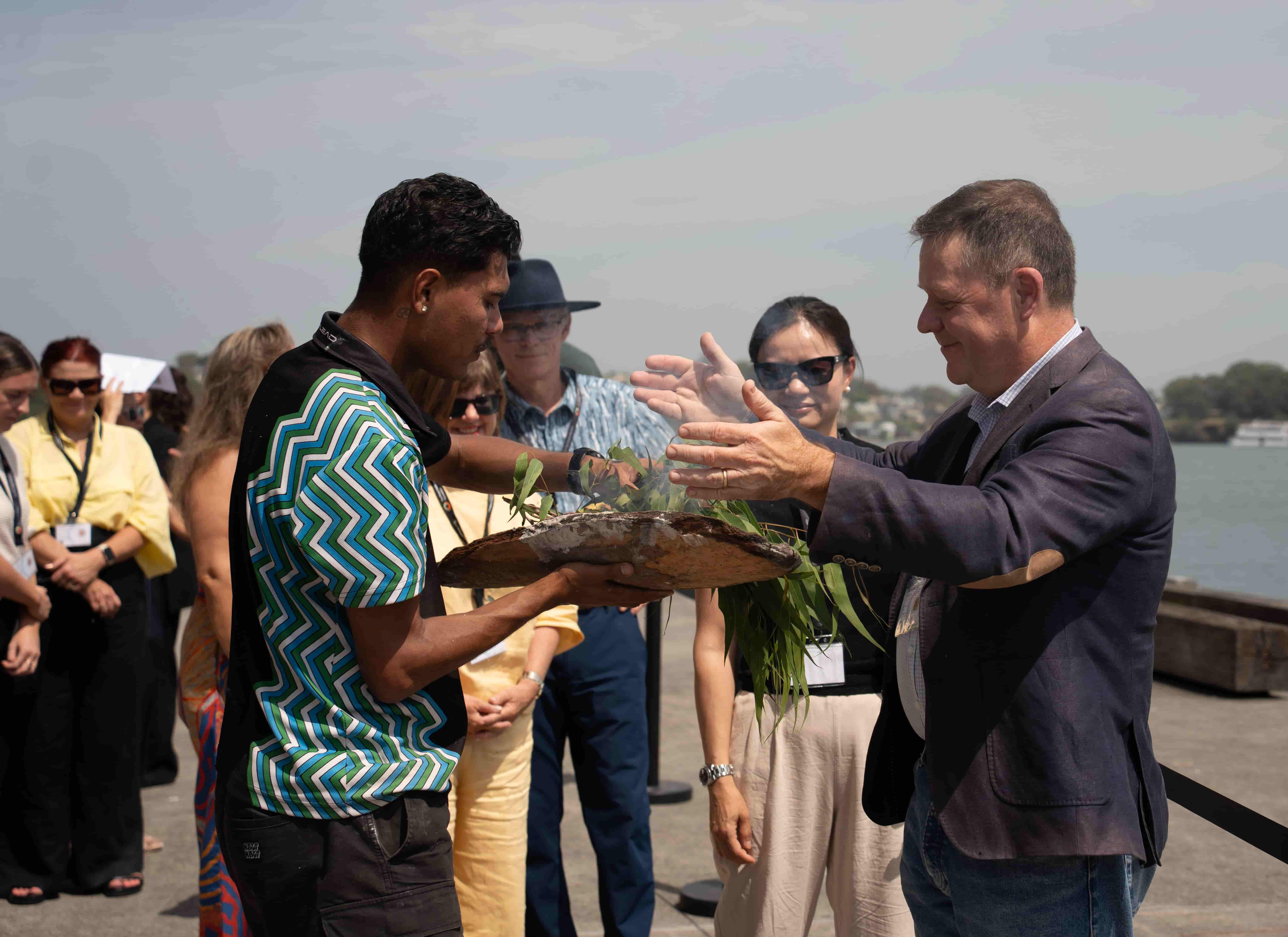 David leads the traditional Smoking Ceremony on Gadigal land, with CEO Ross Piper and other attendees observing the cultural practice.
