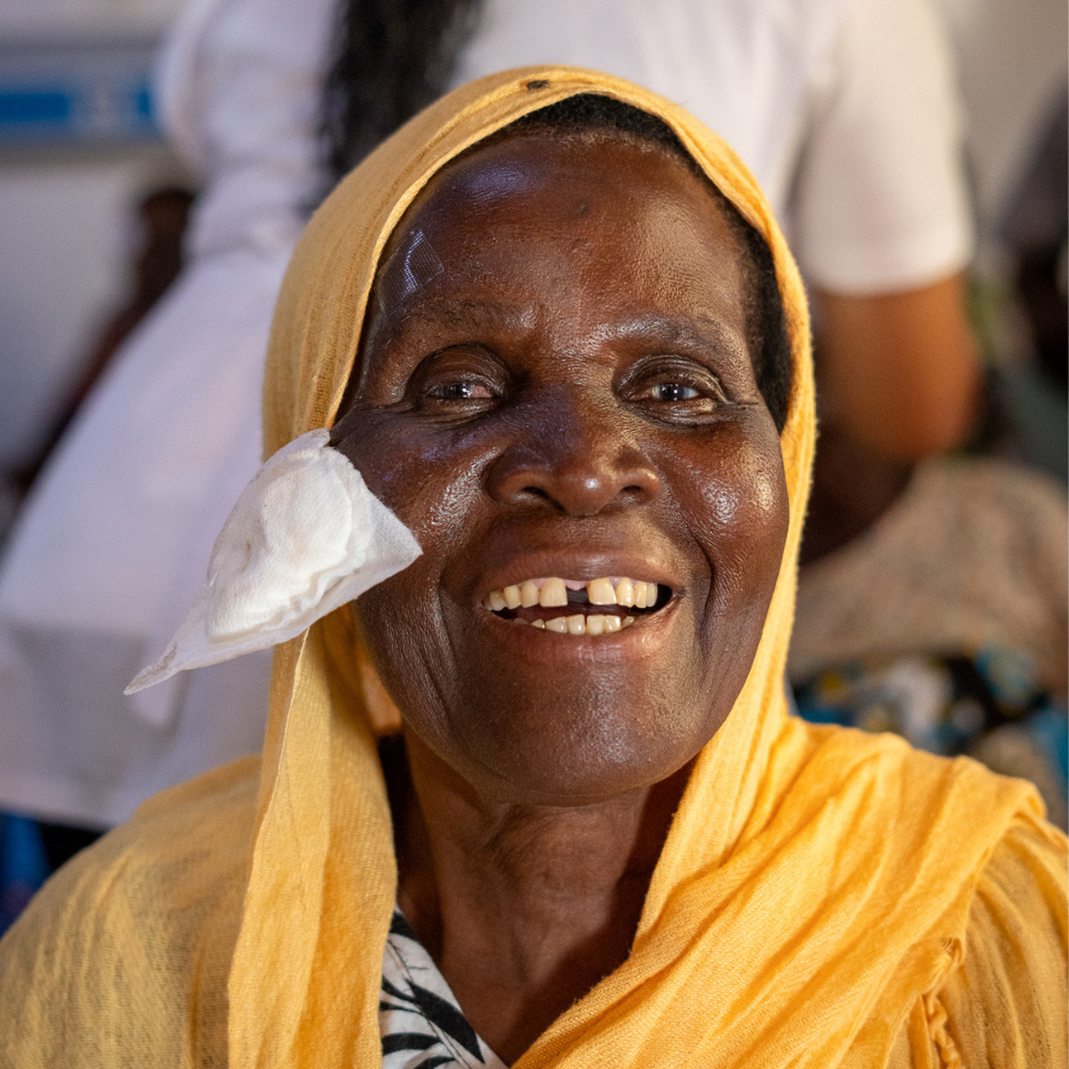 Woman smiling after cataract surgery as her eye patch is removed at a Kilifi eye camp in Kenya