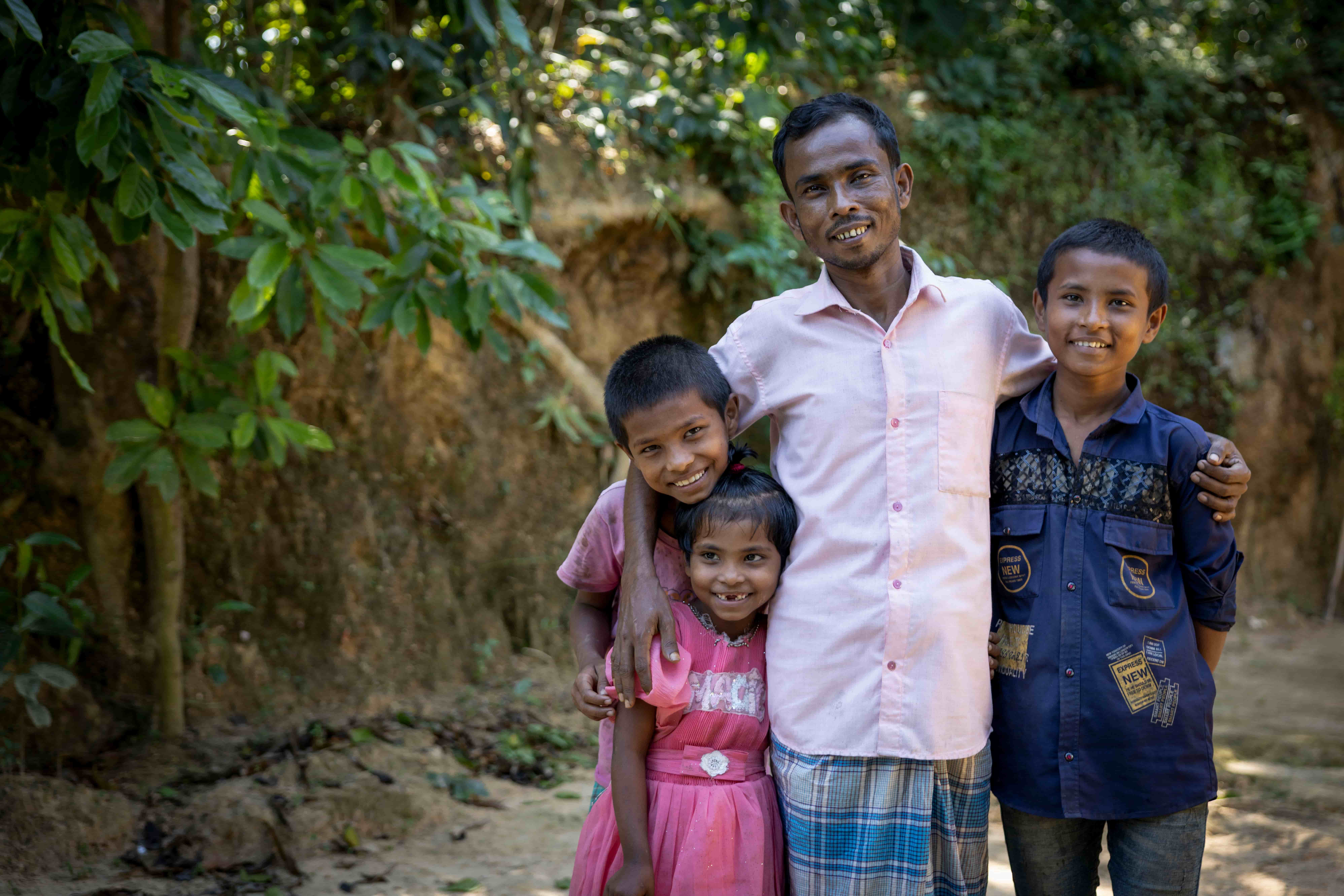 Obaidul stands outside his home with his three children in Cox&rsquo;s Bazar, seeing clearly for the first time in years after cataract surgery.