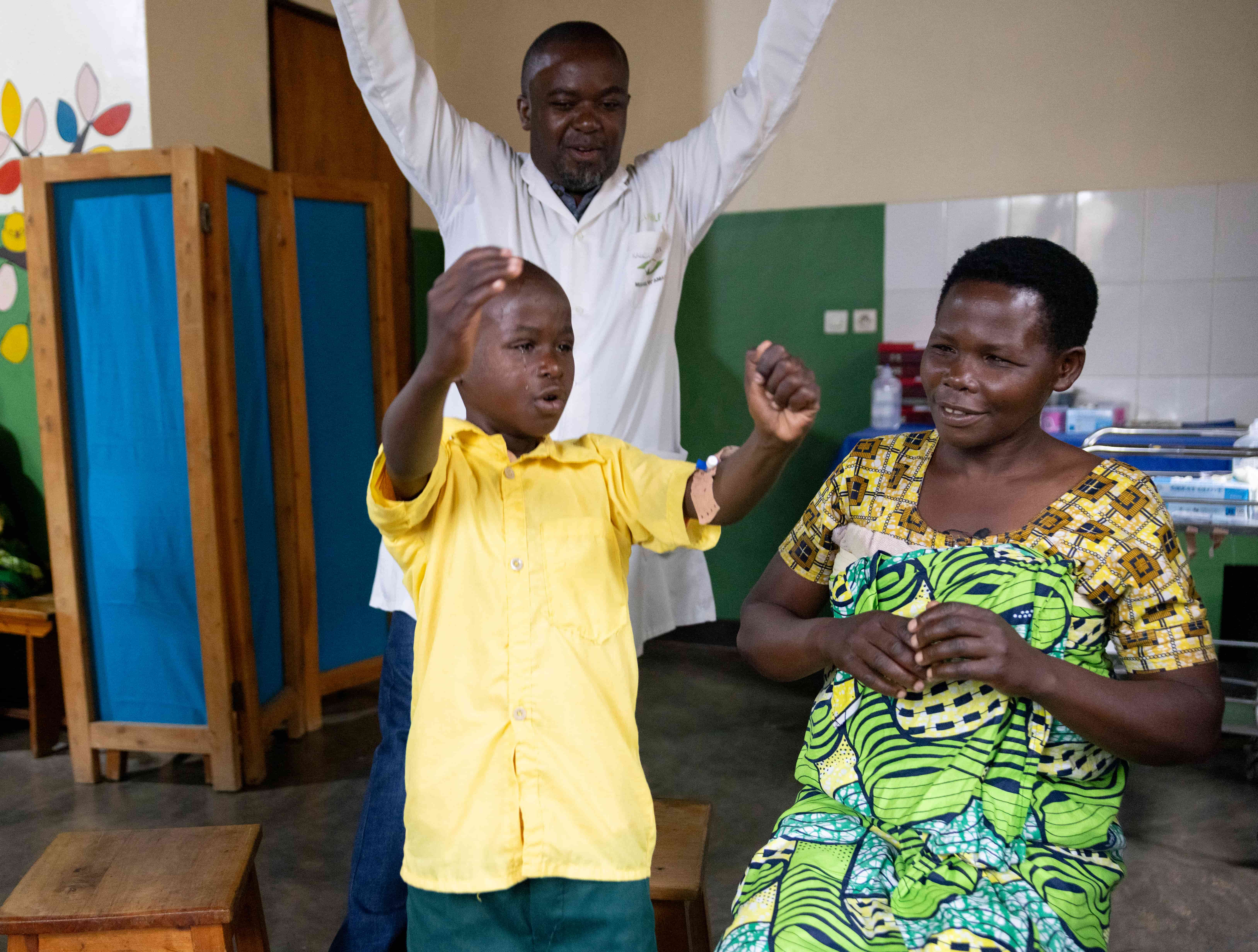 Dr Tuyisabe Theophile and 8-year-old Raban celebrating after his patch was removed, both raising their arms in joy at restored sight.