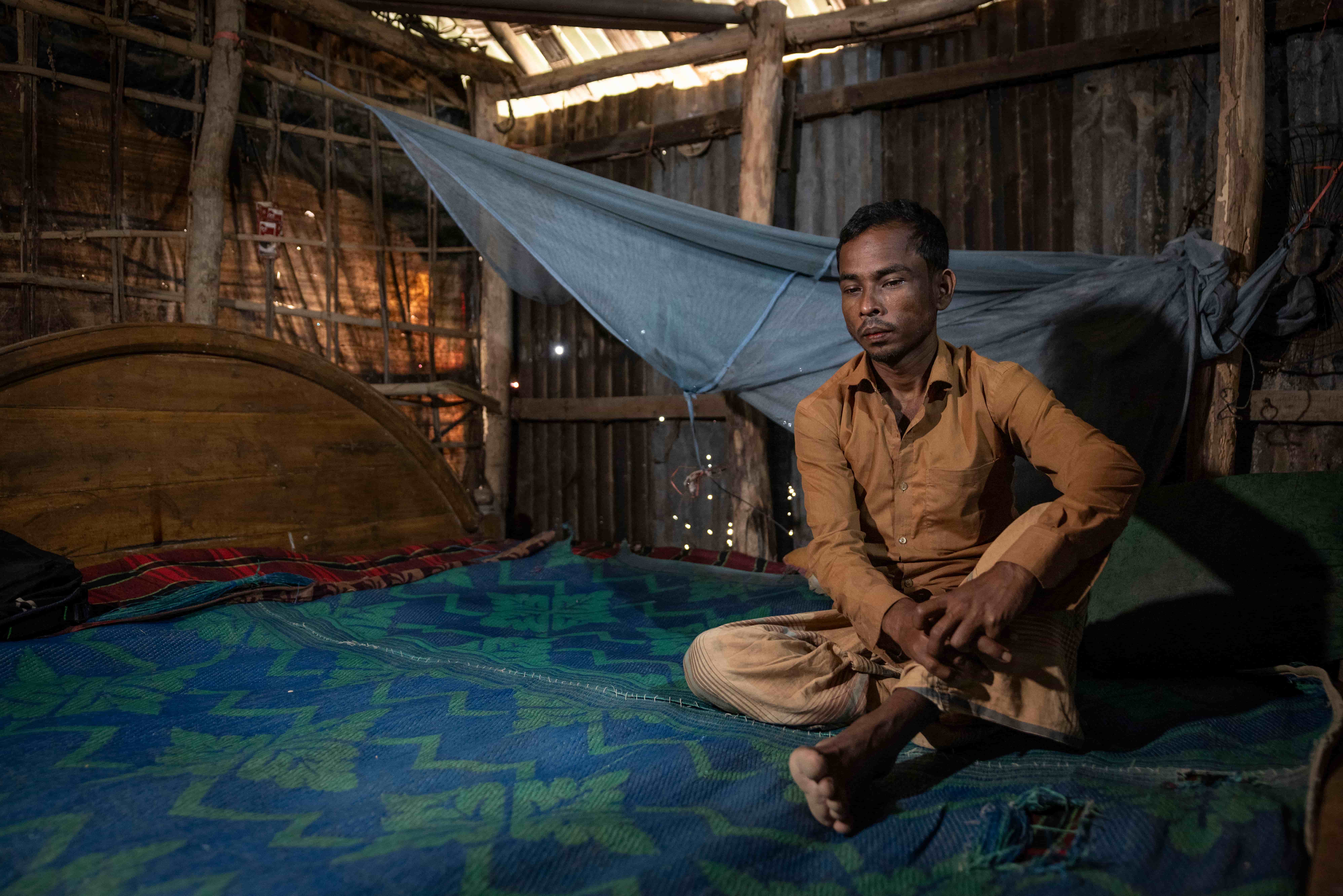 Obaidul sits quietly in his modest home in Cox’s Bazar. Low light filters into the darkened room.