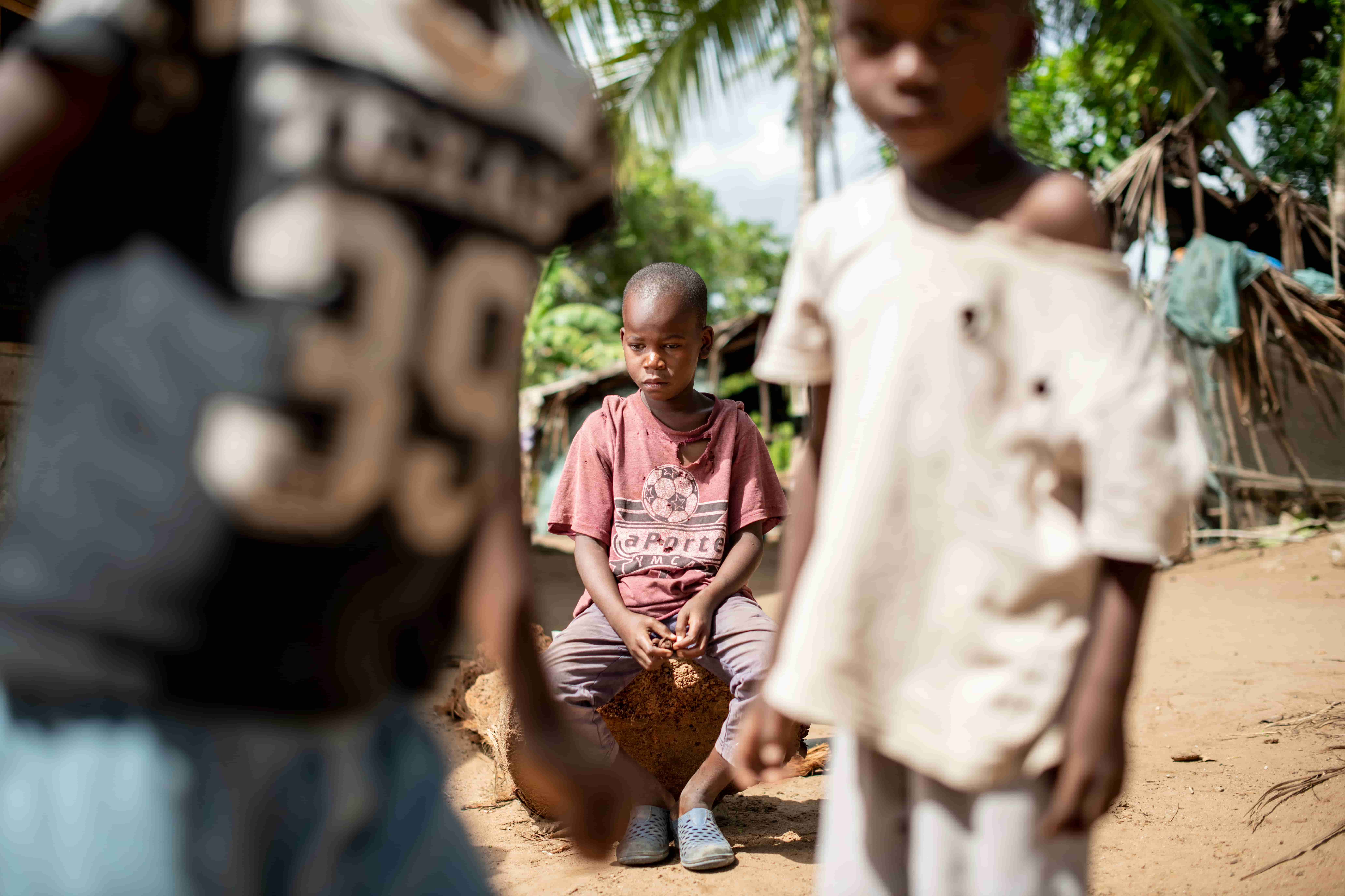 Mbaruku sits on the sidelines watching other children play soccer before his cataract surgery.