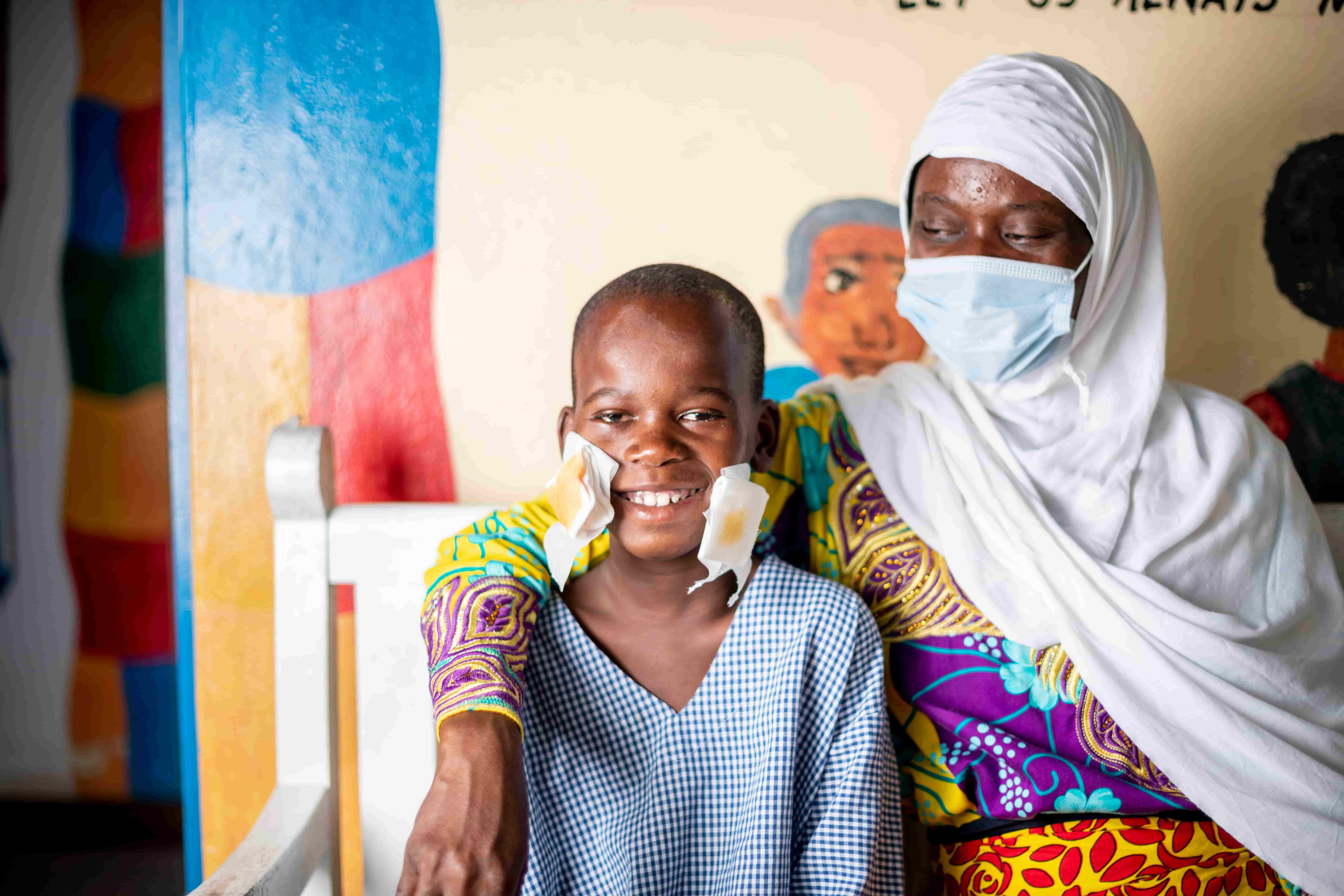 Mbaruku and his mother Mwajungu celebrating after his sight-restoring surgery as his eye patch is removed.