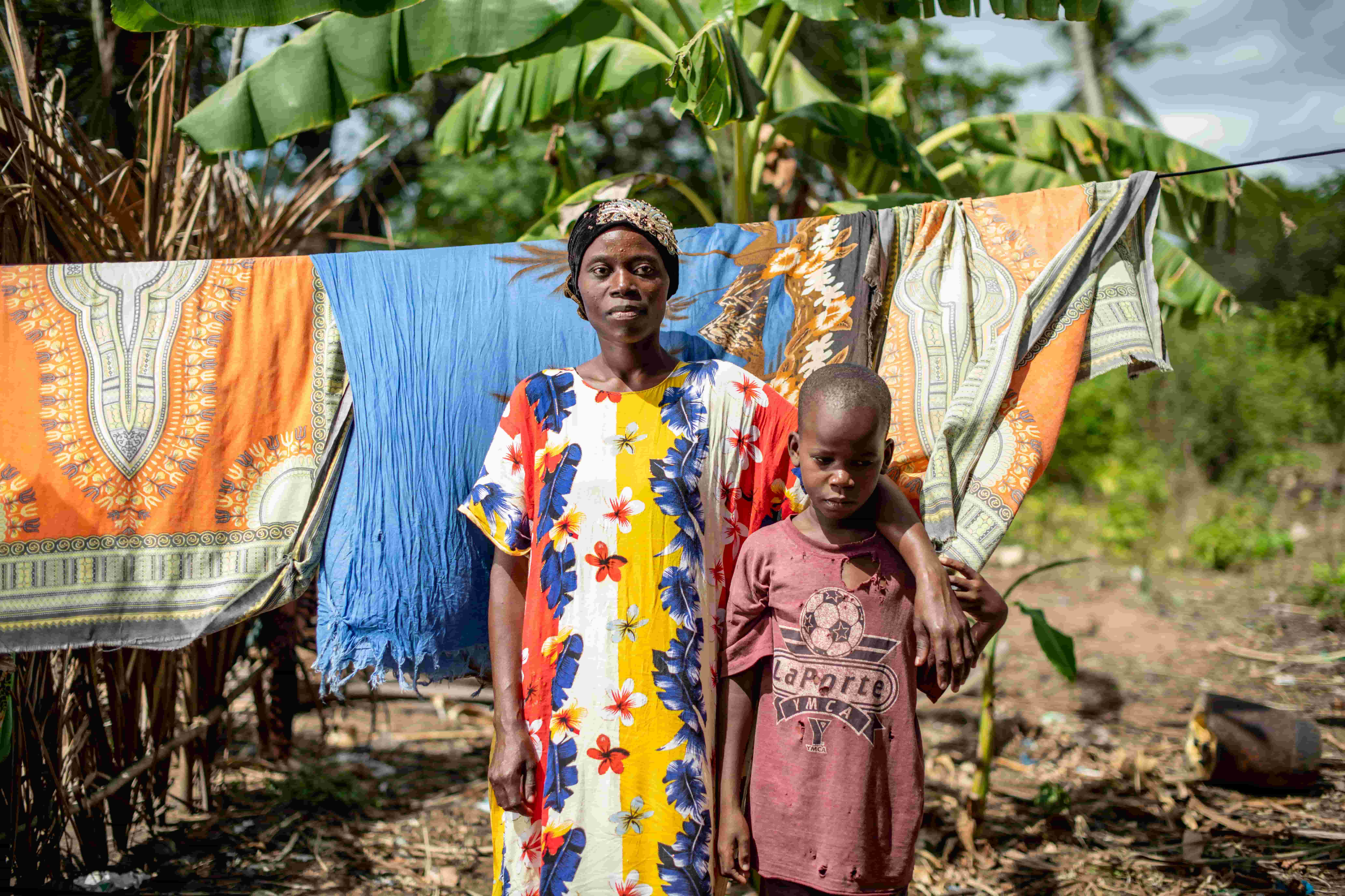 Mbaruku and his mother Mwajungu stand outside their home in front of a washing line.
