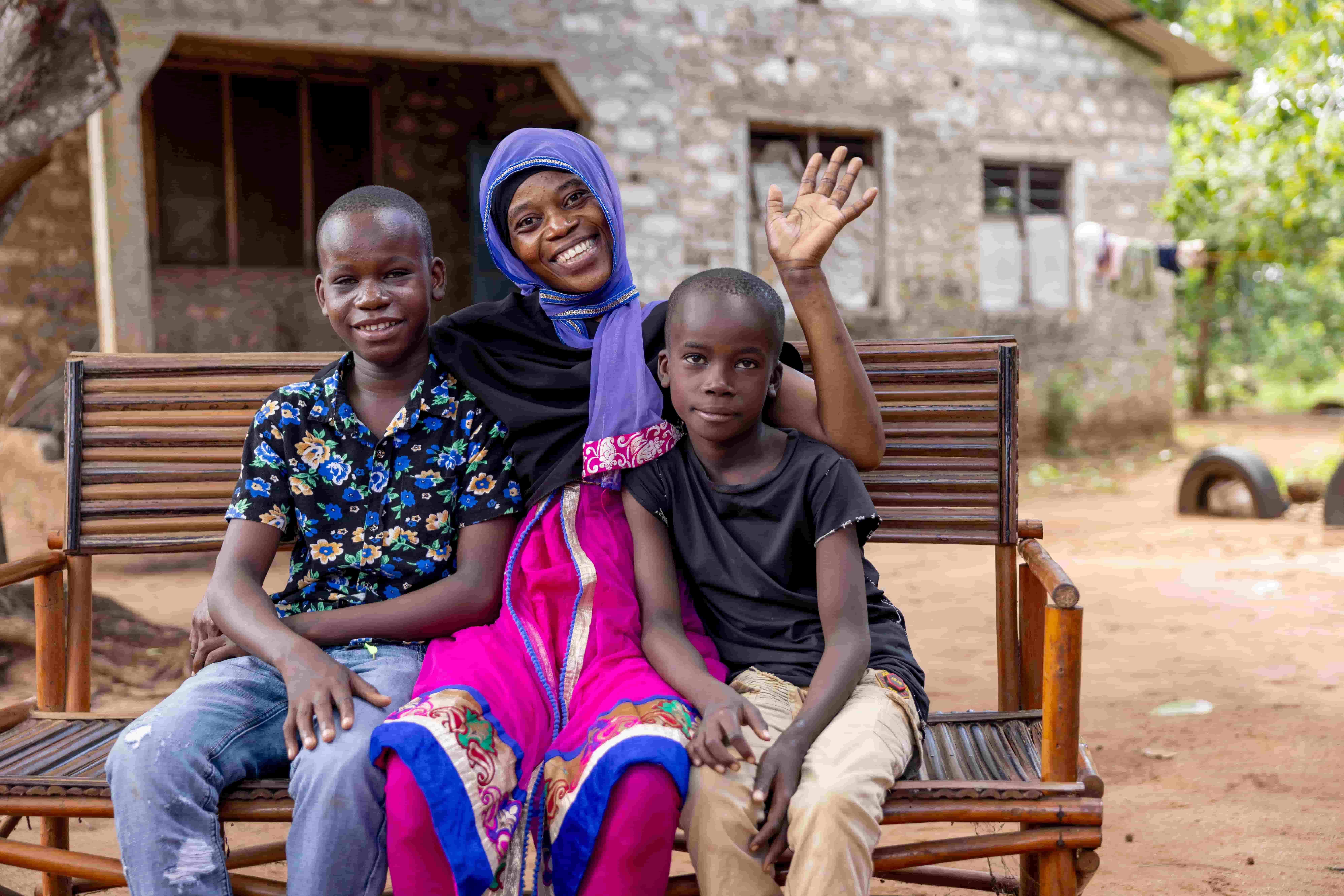 Mbaruku sits with his mother Mwajungu and his brother, smiling together after his sight-restoring surgery.