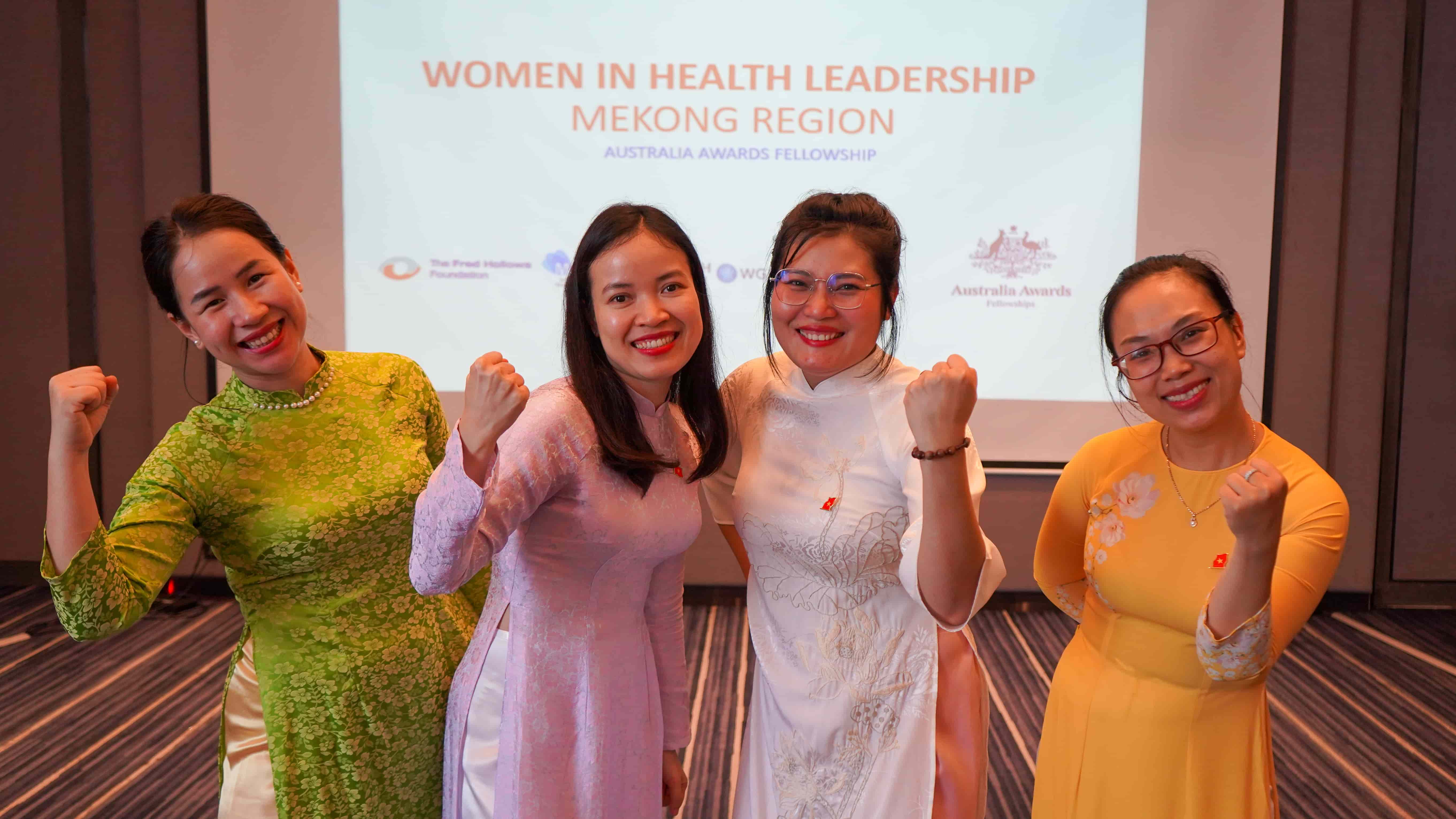 Women health leaders from the Mekong region stand together in front of a projector screen during the Australia Awards Fellowship program.