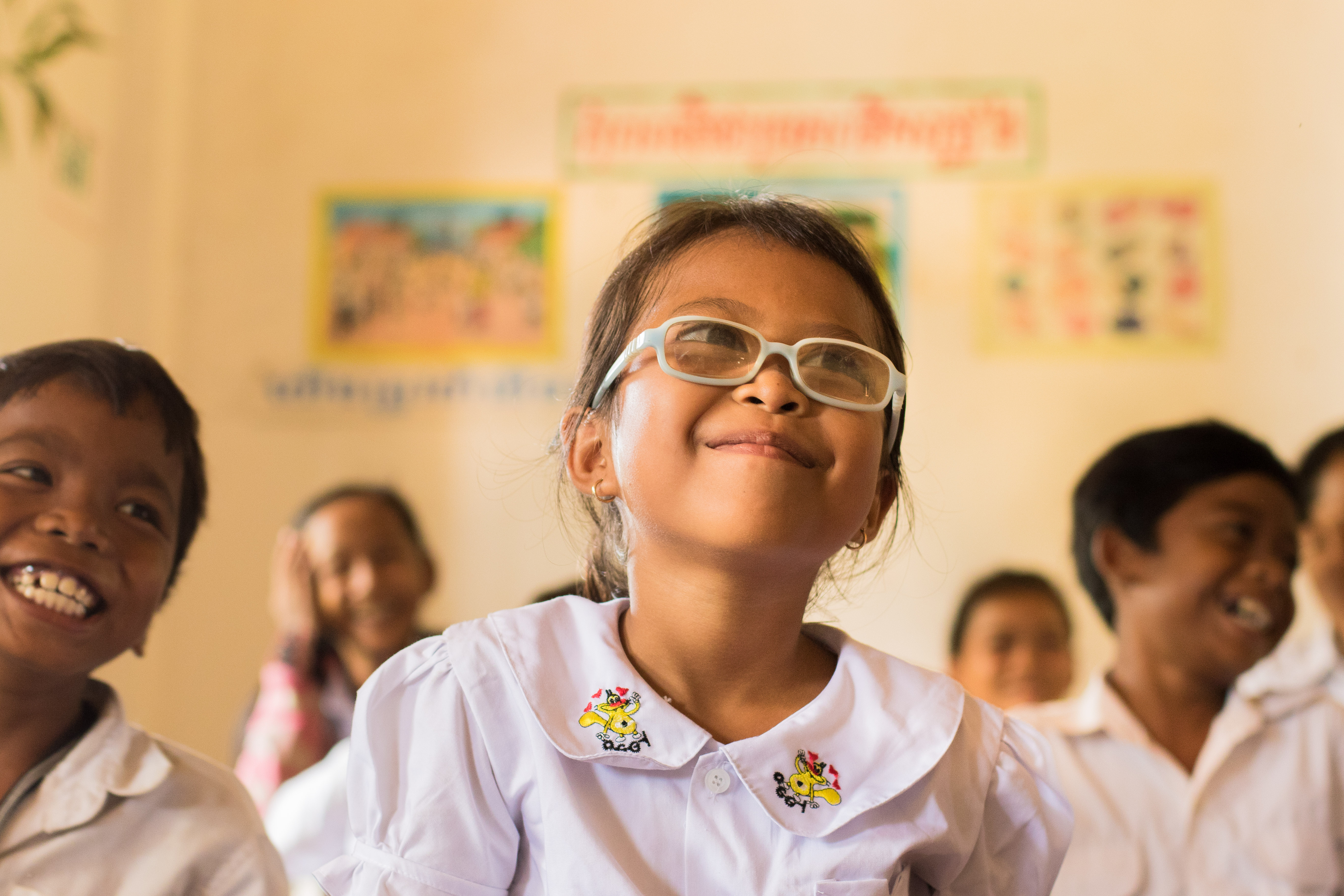 Vann sitting at her desk at school, smiling wide while she learns from her teacher